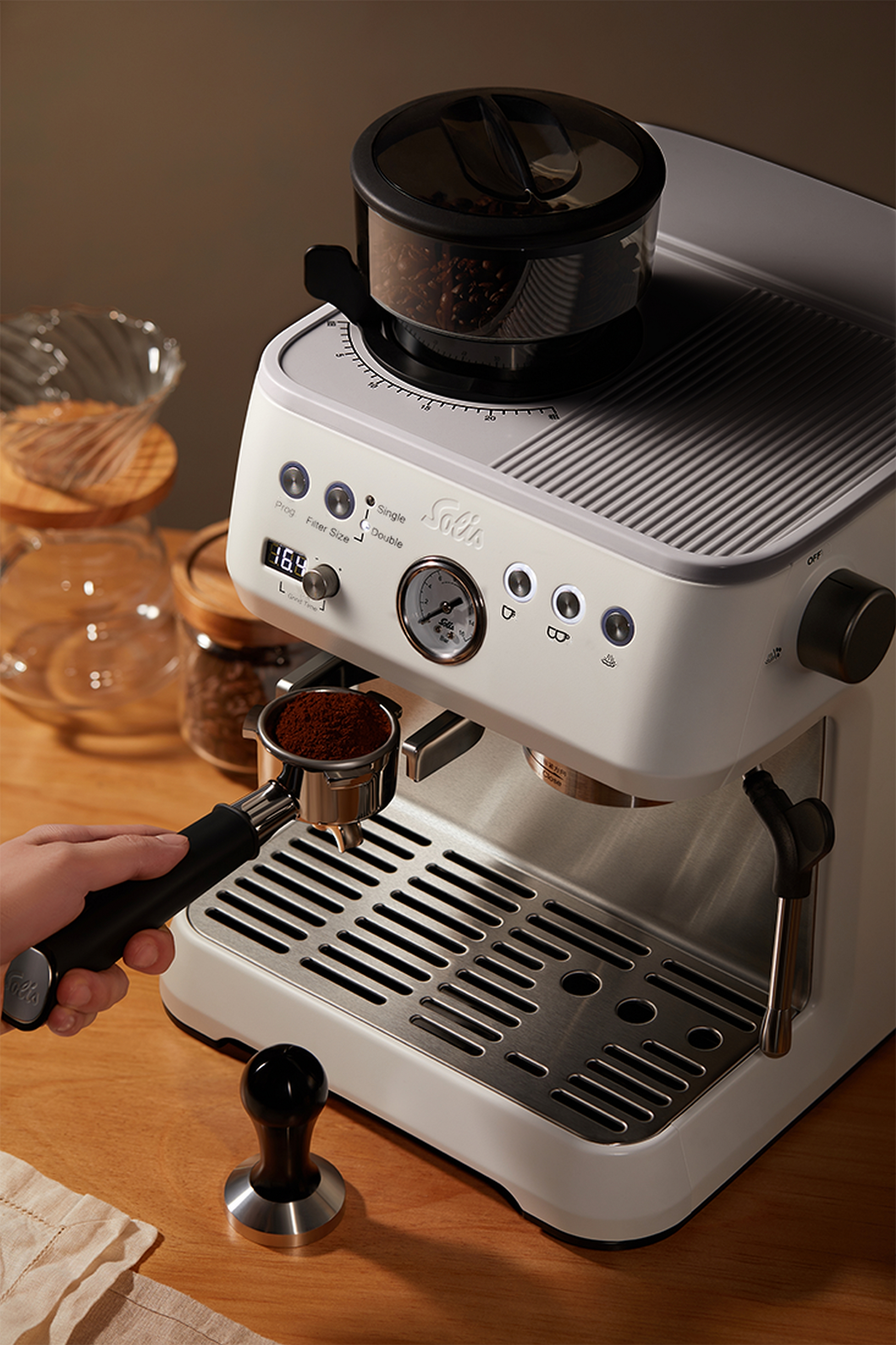 Eine weiße Espressomaschine mit Siebträger voller Kaffeepulver.