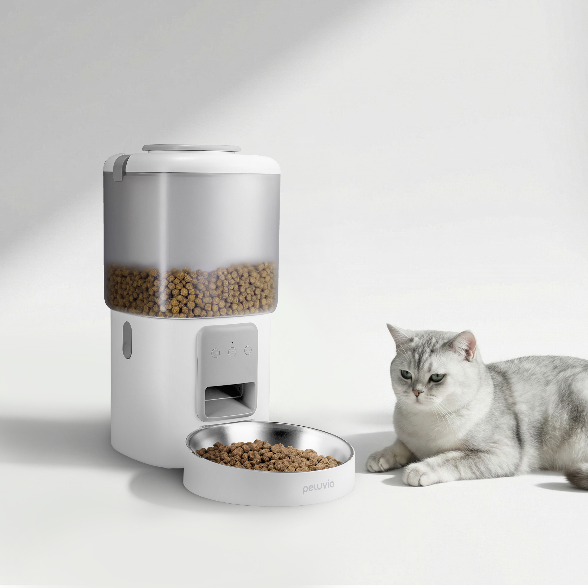 Ein weißer Futterautomat mit Futter und eine Katze daneben.