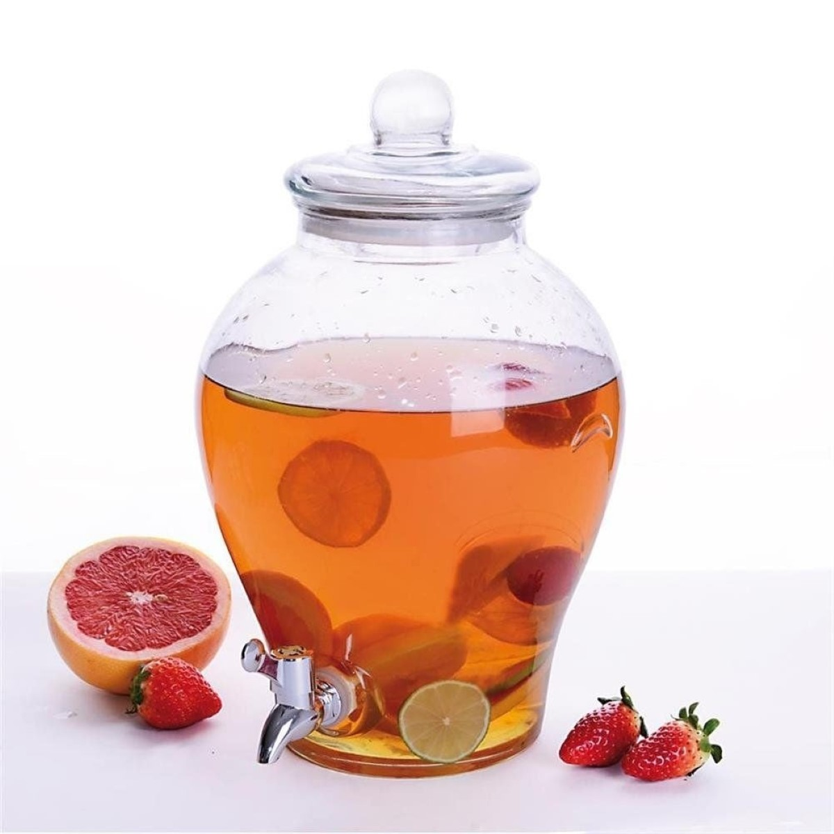 Un dispensador de vidrio con grifo, lleno de bebida de naranja y rodajas de fruta.