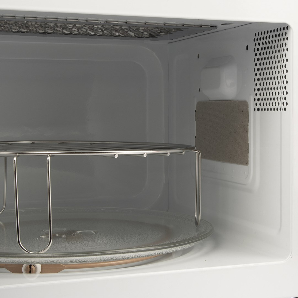 Interno di un forno a microonde con piatto girevole in vetro e griglia.