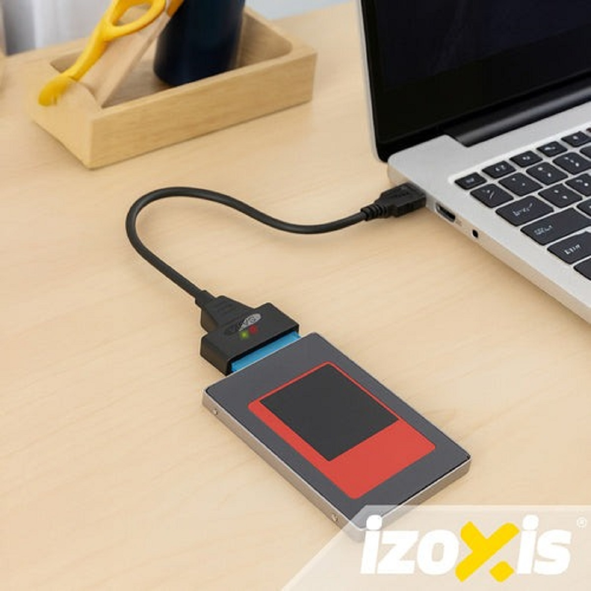 Disco SSD conectado a portátil con adaptador, sobre escritorio madera.