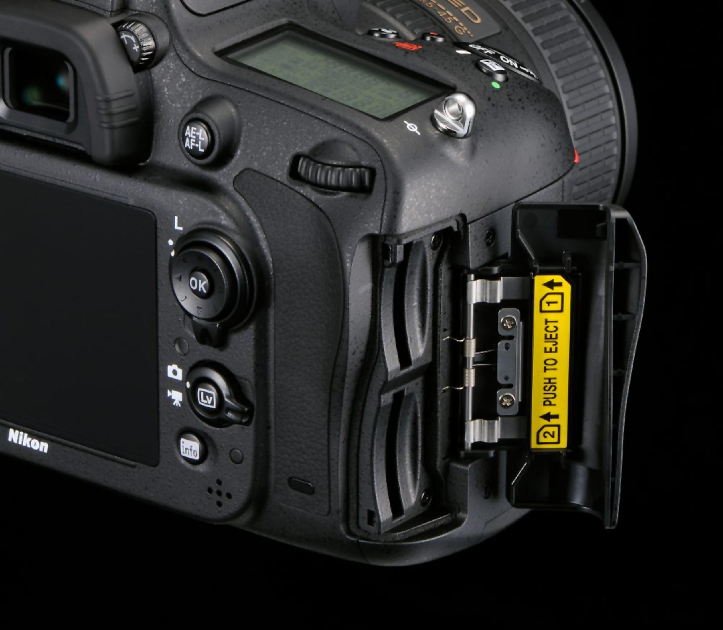 Nikon Kamera mit geöffnetem Batteriefach und gelbem Ejektionshebel.