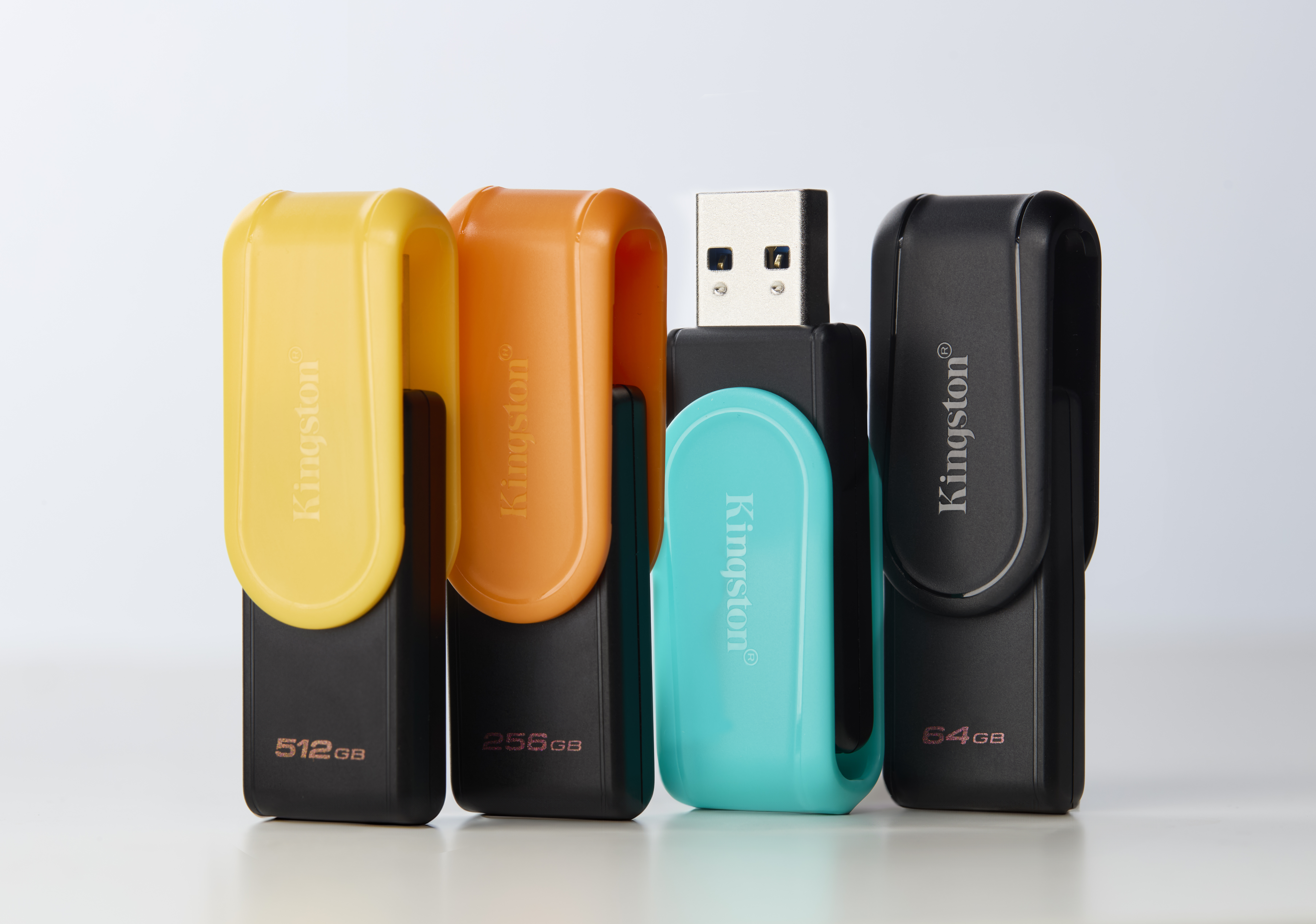 Vier Kingston USB-sticks: geel (512GB), oranje (256GB), turquoise en zwart (64GB).