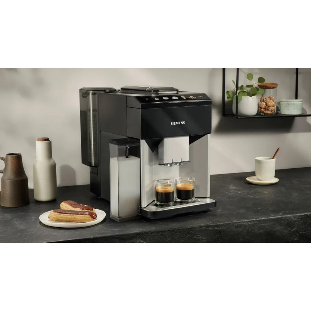 Ekspres do kawy z dwoma espresso, dzbankiem na mleko, ciastkami na talerzu.