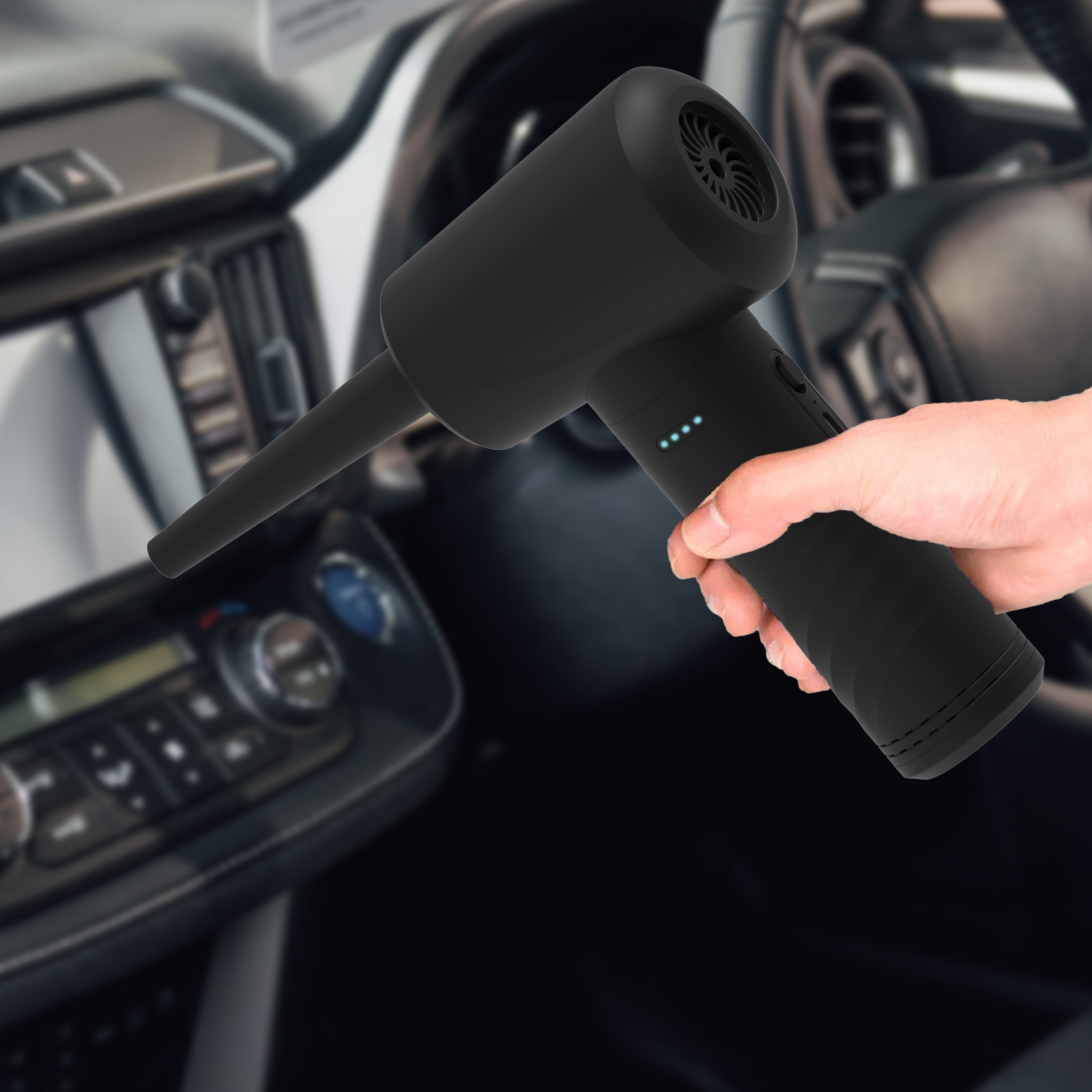Black handheld vacuum cleaner held in a car, interior blurred.