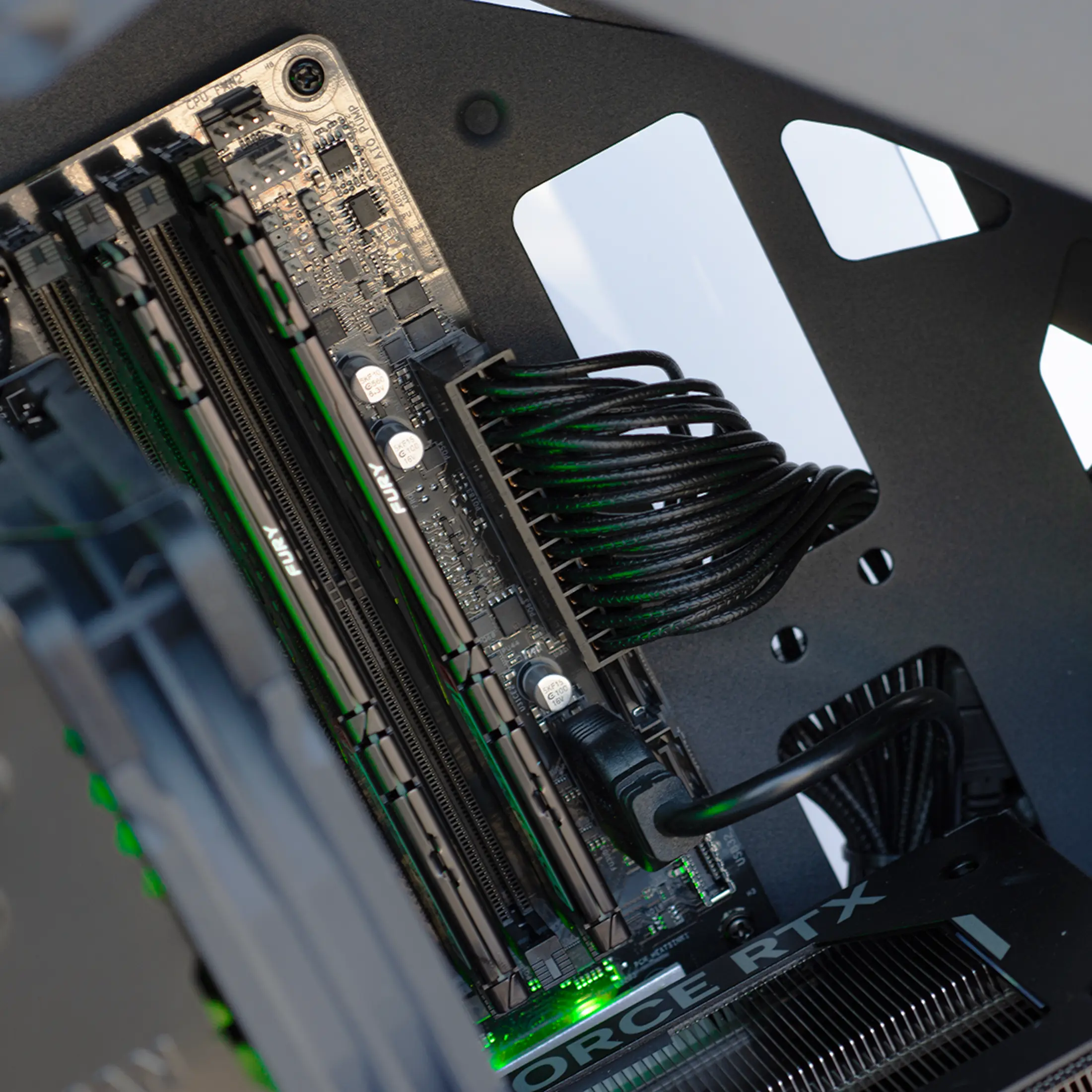 A computer motherboard with RAM sticks, cables, and a graphics card.