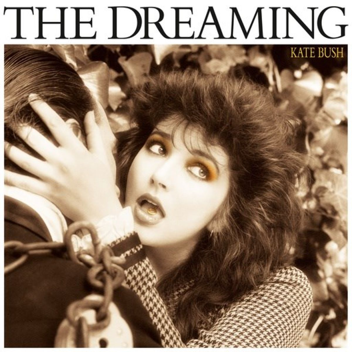 Kate Bush con catena e anello dorato in bocca, primo piano.