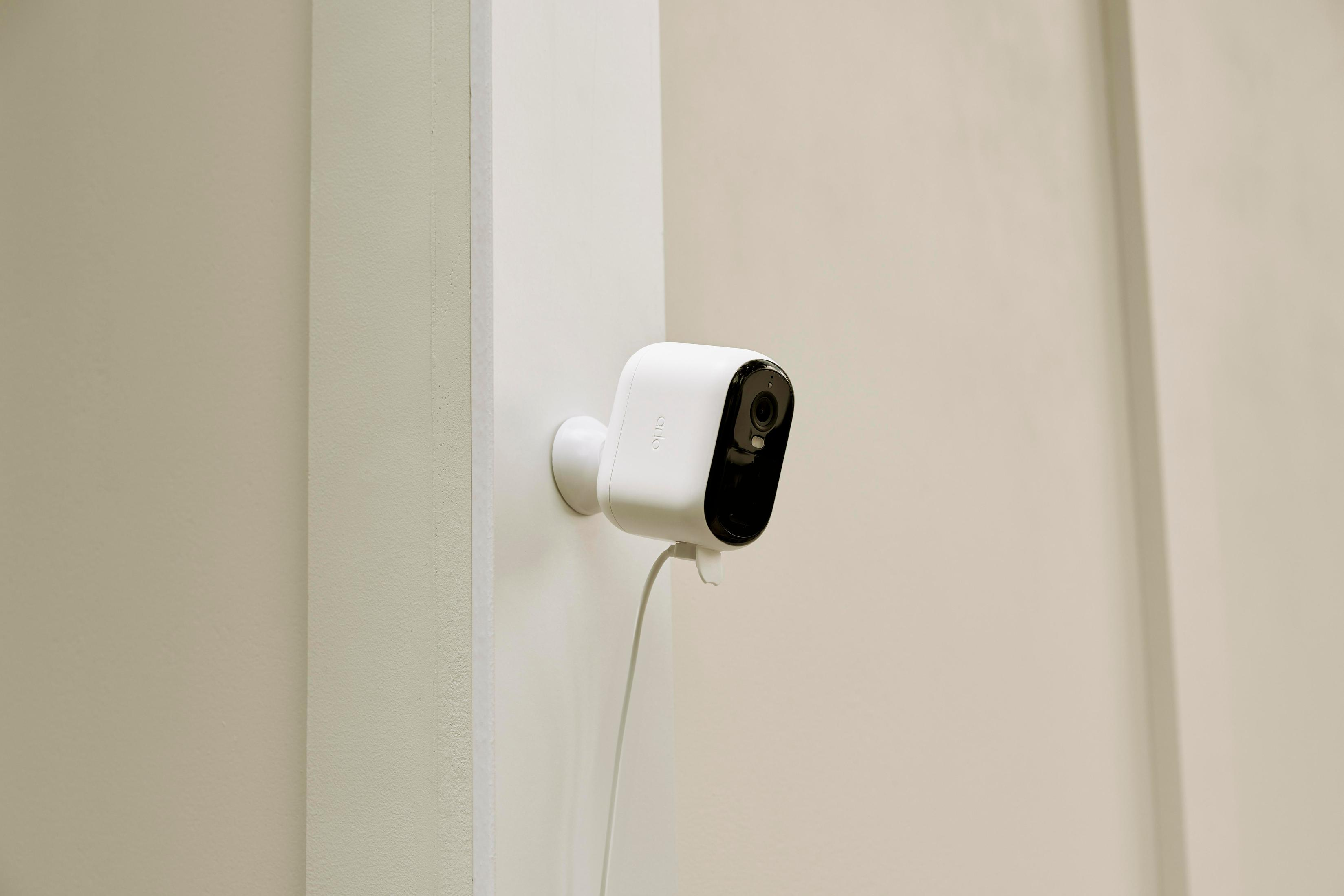 Una telecamera di sicurezza bianca è montata su un muro, con un cavo che pende.
