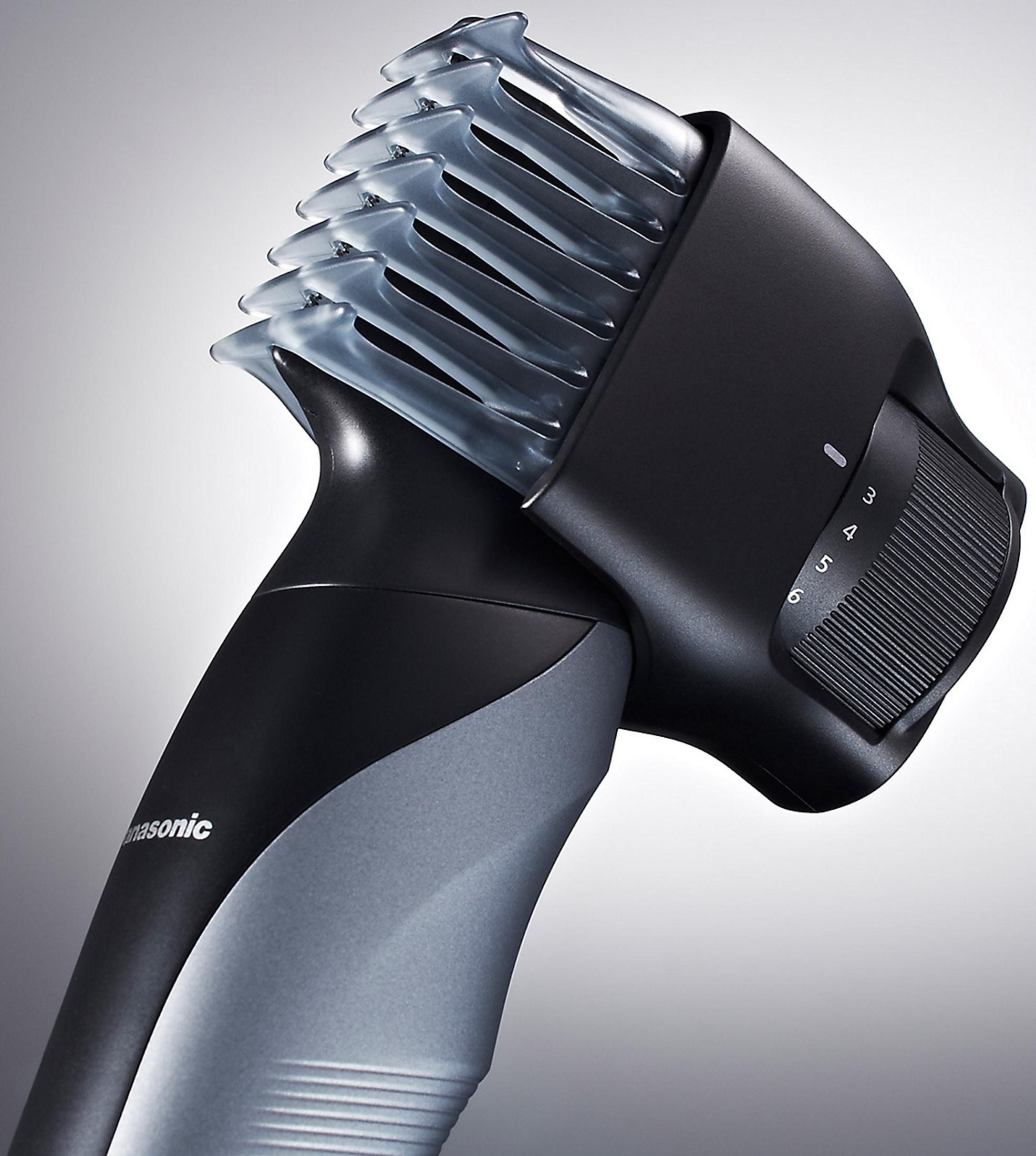 Un rasoio elettrico nero e grigio con un accessorio pettine grigio traslucido, dotato di una rotella di regolazione numerata.