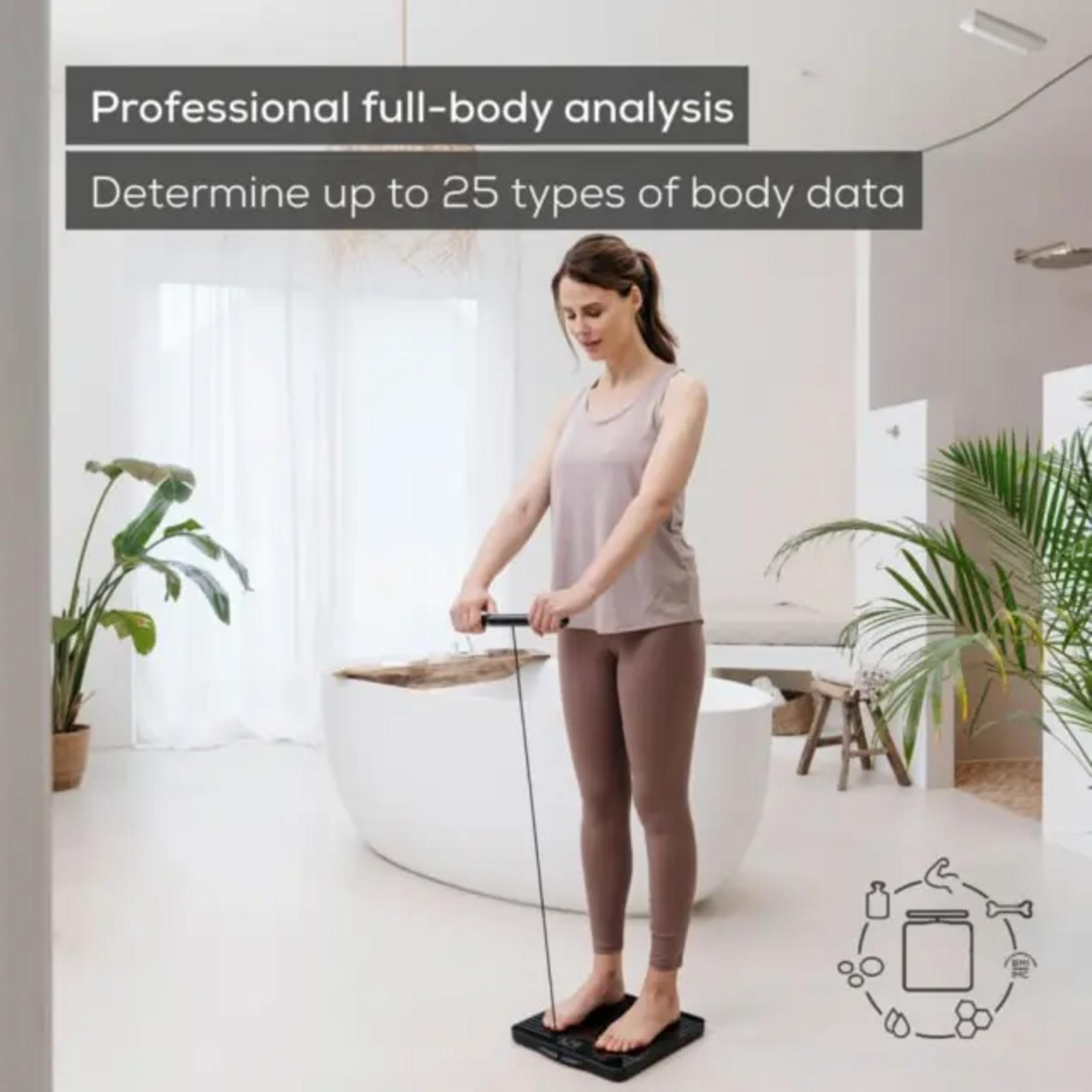 Eine Frau steht auf einer schwarzen Körperanalysewaage mit einem Kabel.
