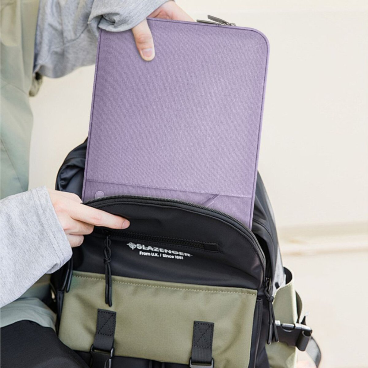 Eine Person steckt eine lila Hülle in einen Rucksack.