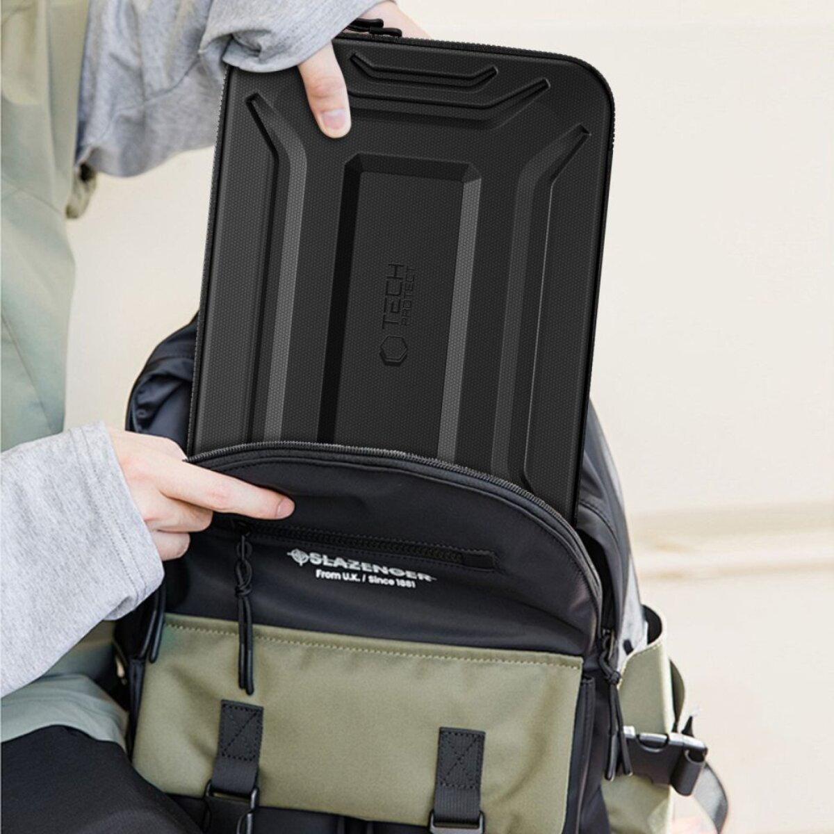 Jemand legt eine schwarze Schutzhülle in einen Rucksack.