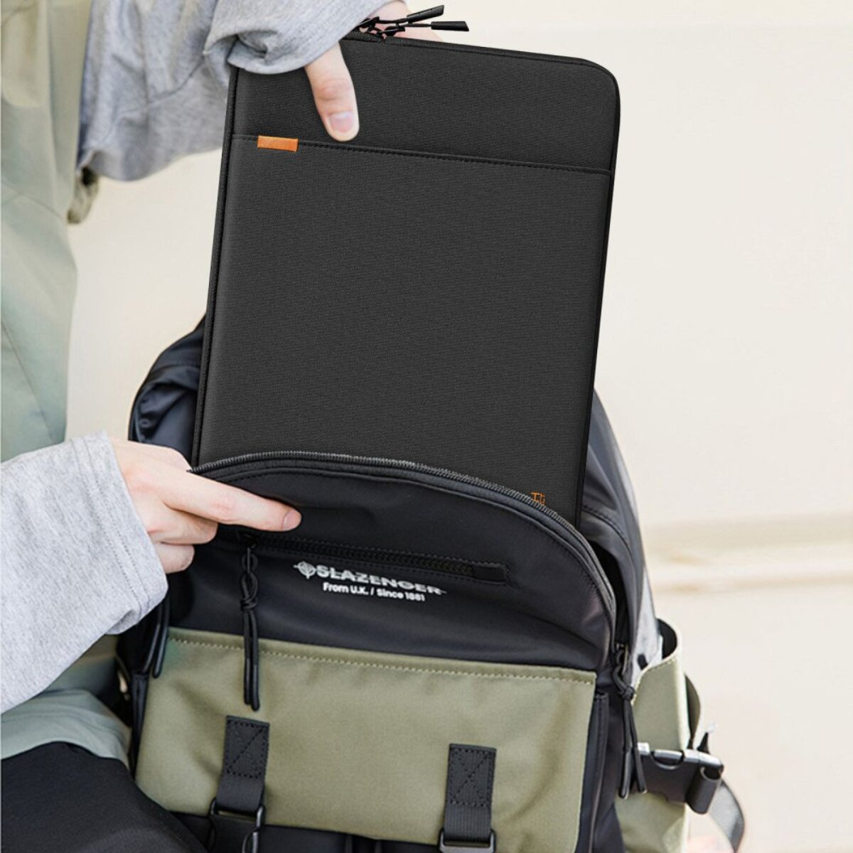 Eine Person packt eine schwarze Laptoptasche in einen Rucksack.