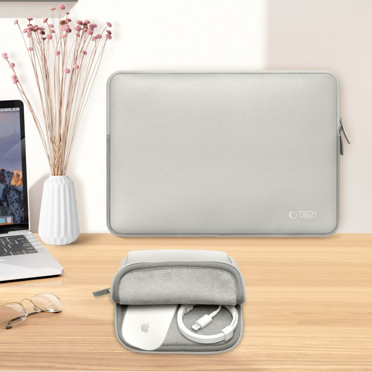 Eine hellgraue Laptoptasche und eine Tasche mit Zubehör auf einem Holztisch.
