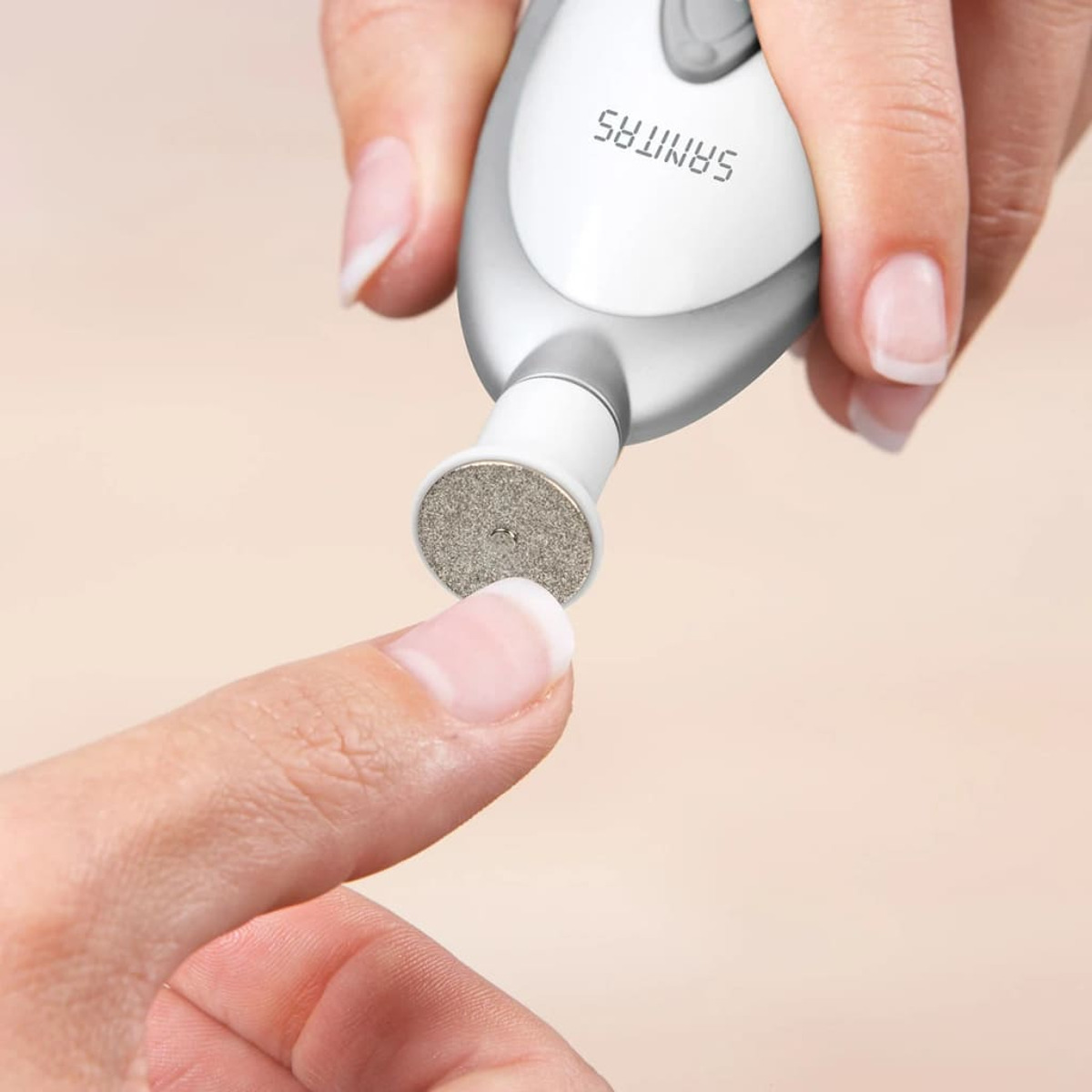 Maniküregerät mit rotierender Feile am Nagel einer Hand.