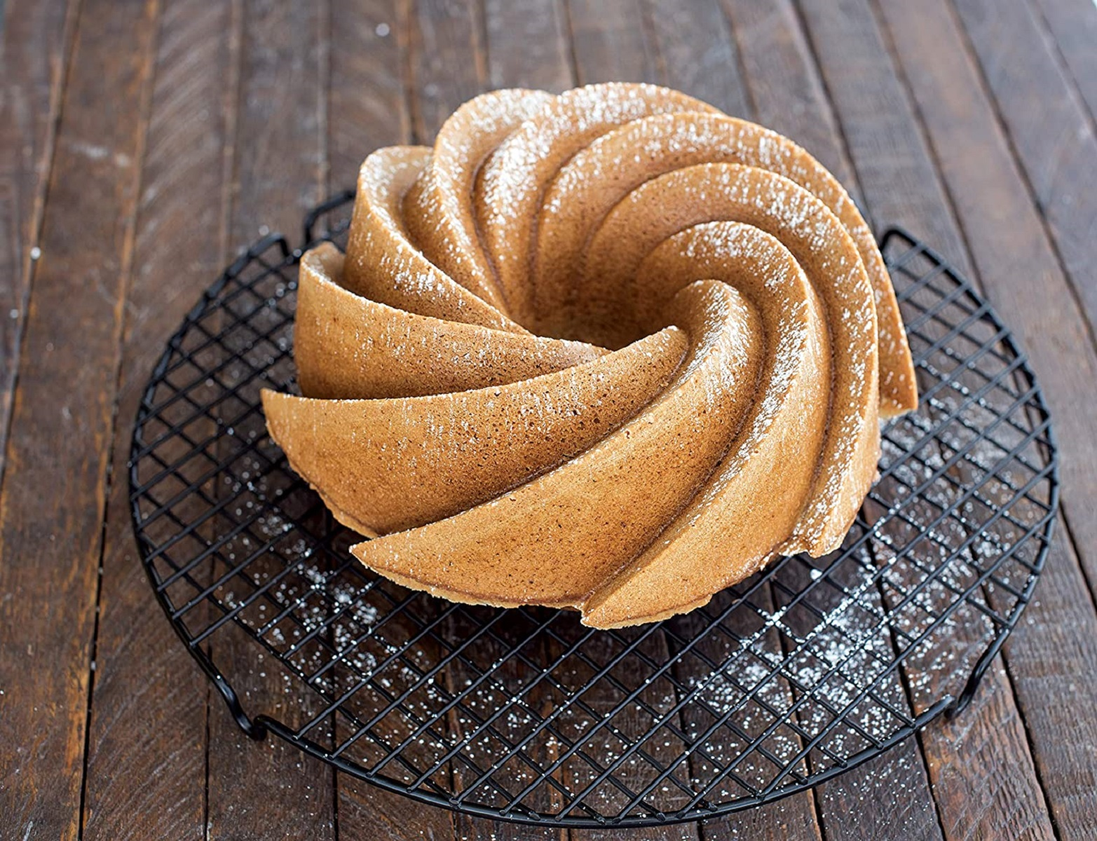 Sarmal bir bundt kek, siyah bir tel üzerinde pudra şekeri serpilmiş.