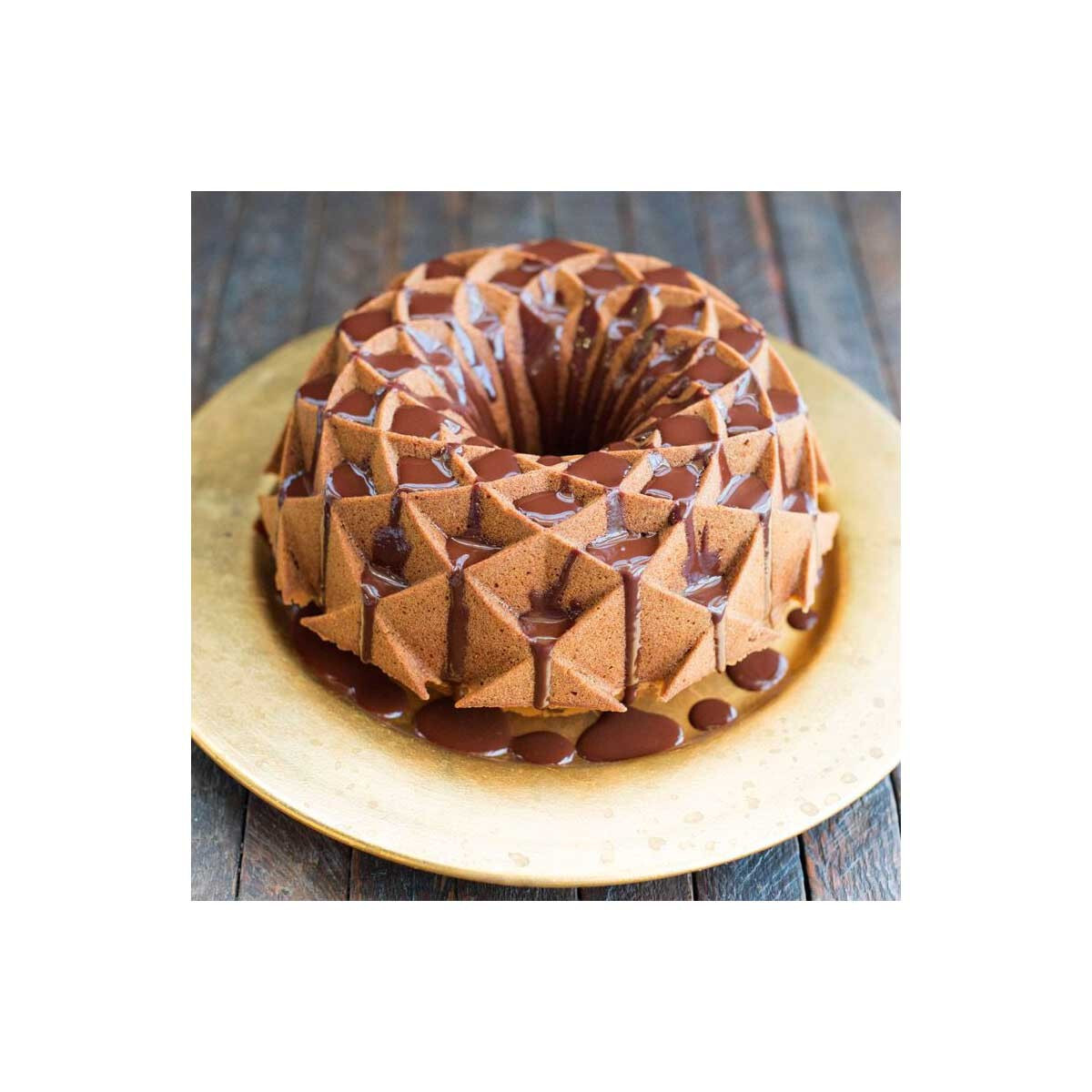 Altın kaplama tabakta çikolata gezdirilmiş altın rengi Bundt kek.