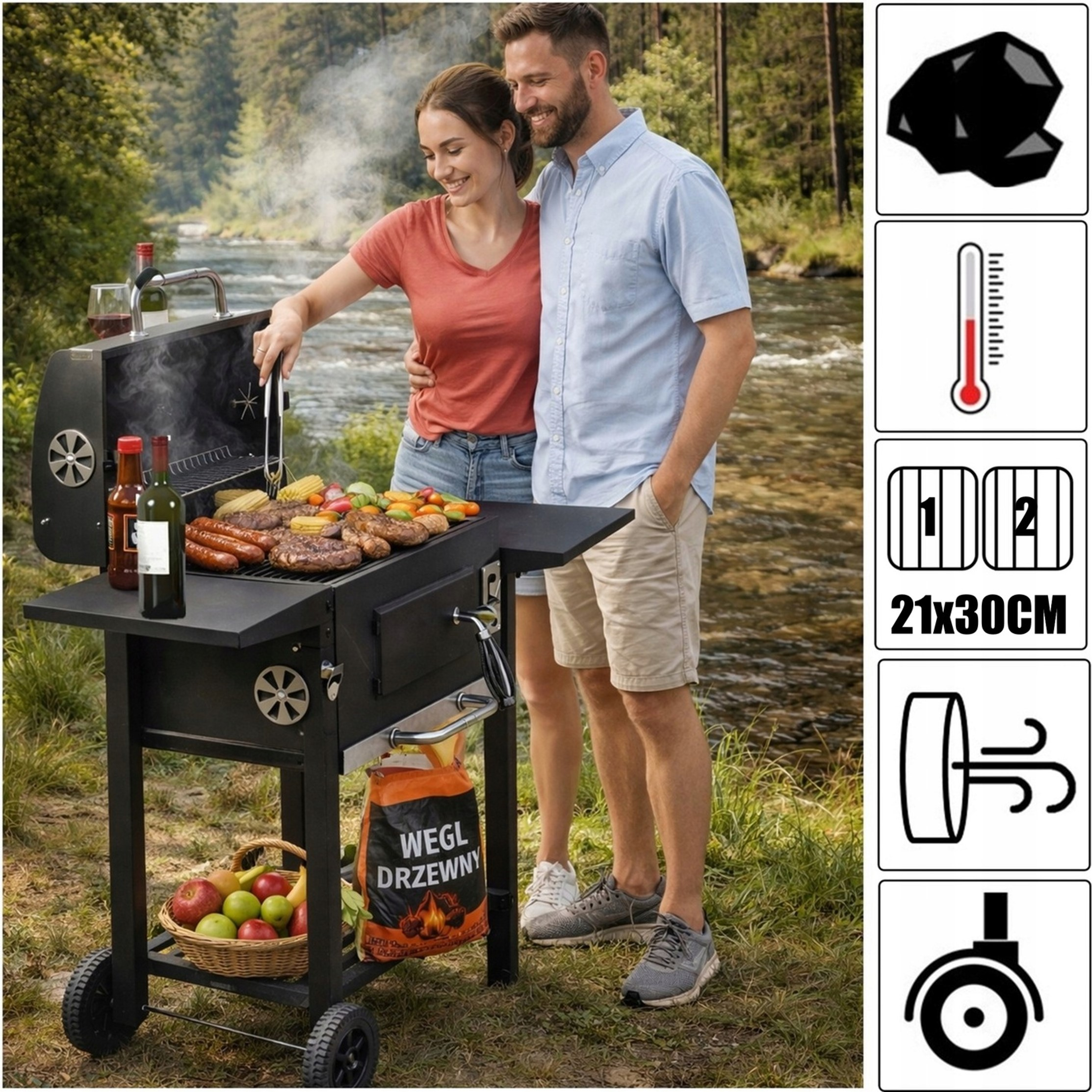 Uśmiechnięta para grilluje nad rzeką z zielonymi drzewami. Mężczyzna obejmuje kobietę, gdy ona zajmuje się grillem z jedzeniem.