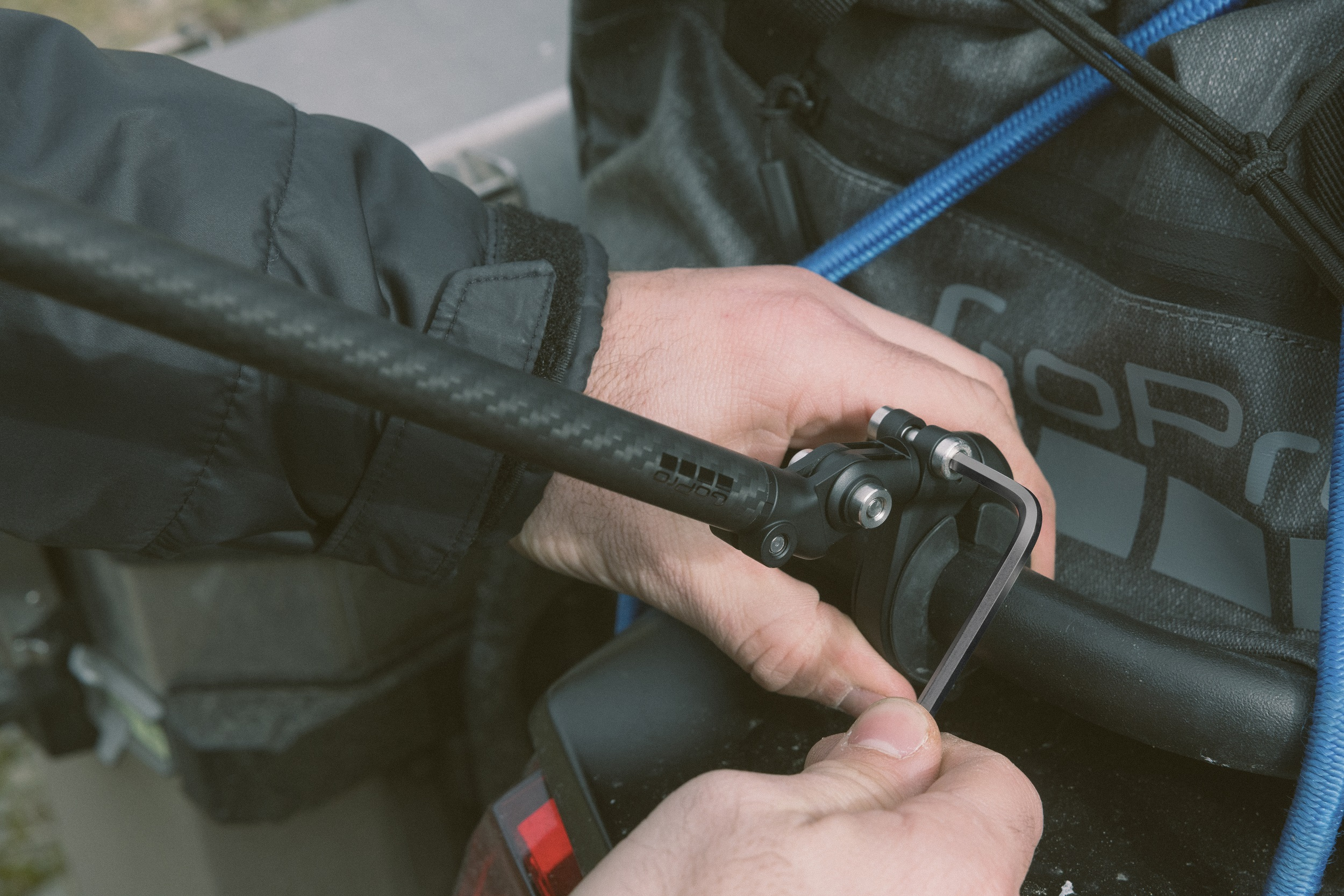 Una persona usa una chiave a brugola per stringere un supporto GoPro su un tubo di carbonio.