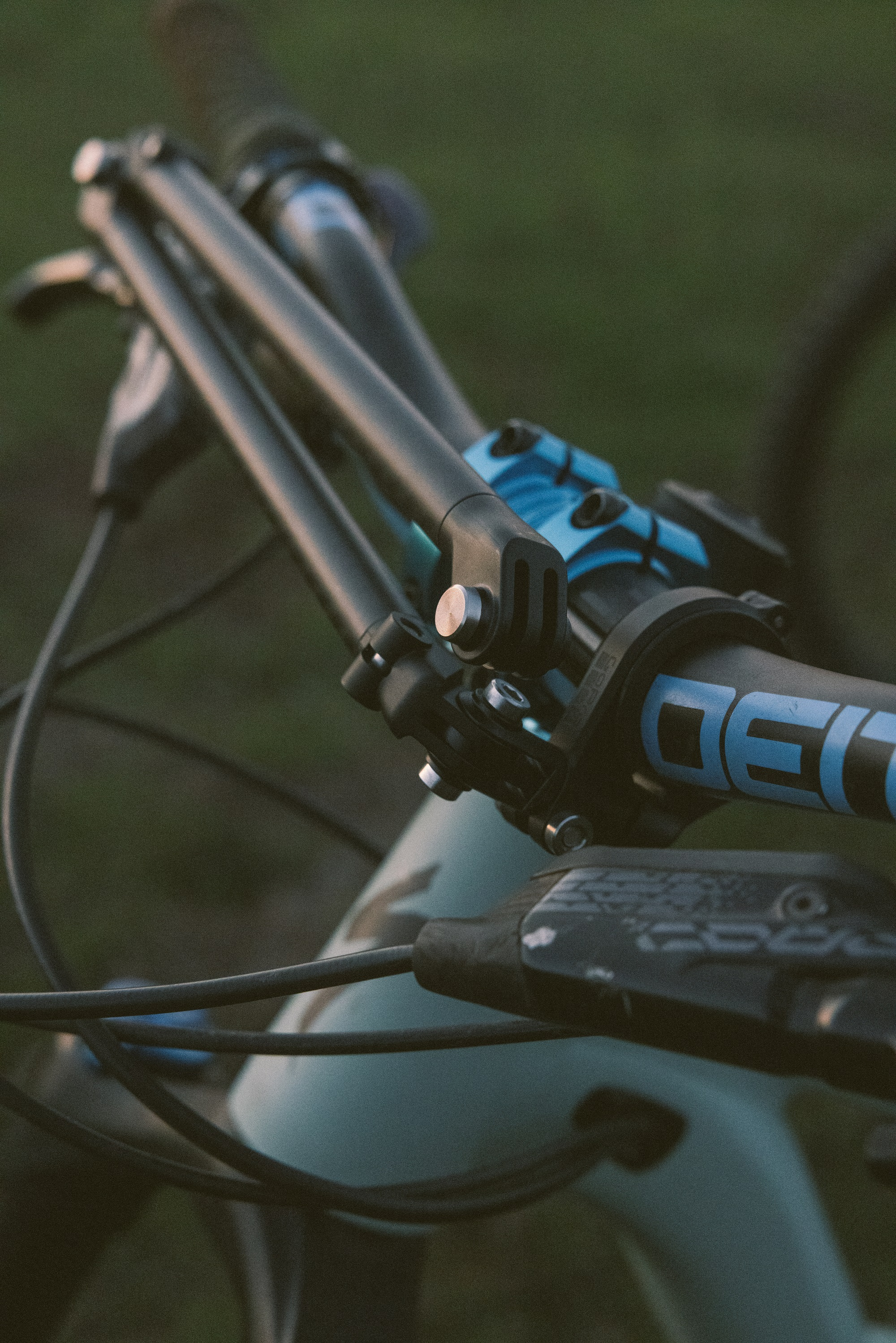 Primo piano del manubrio di una mountain bike con accenti blu e cavi.