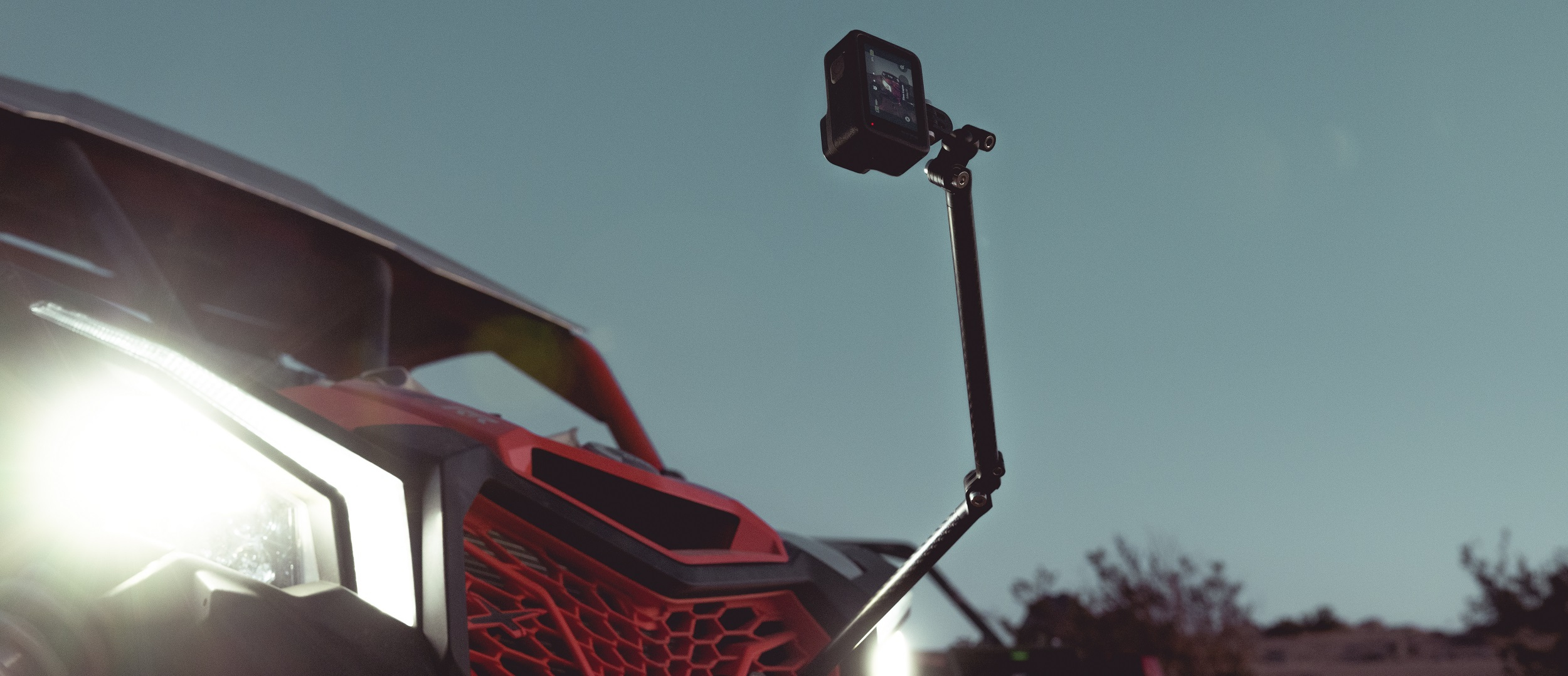 Una action cam su un braccio è attaccata a un veicolo rosso.
