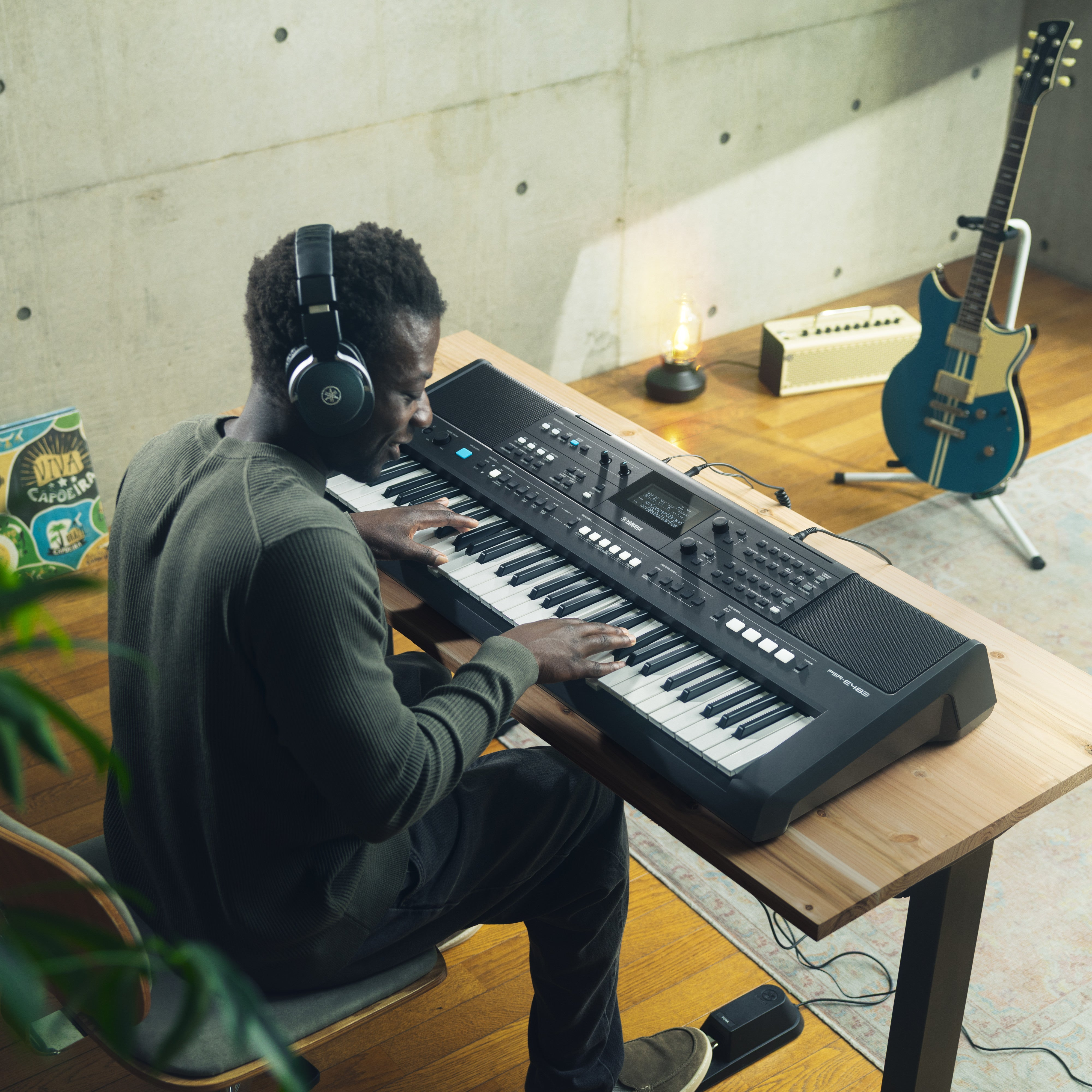 Mężczyzna w słuchawkach gra na keyboardzie, obok stoi gitara.