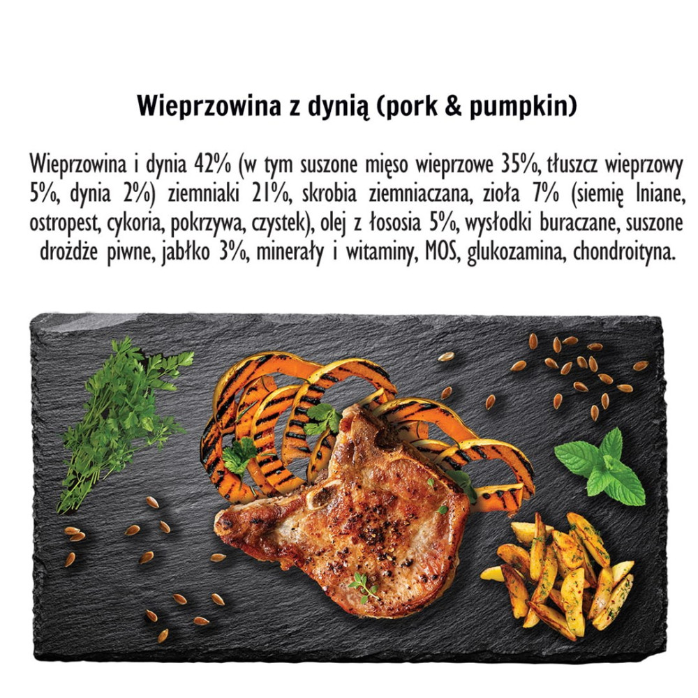 Grillowany kotlet schabowy z wstążkami dyni, ziołami i ćwiartkami ziemniaków na ciemnej desce łupkowej.