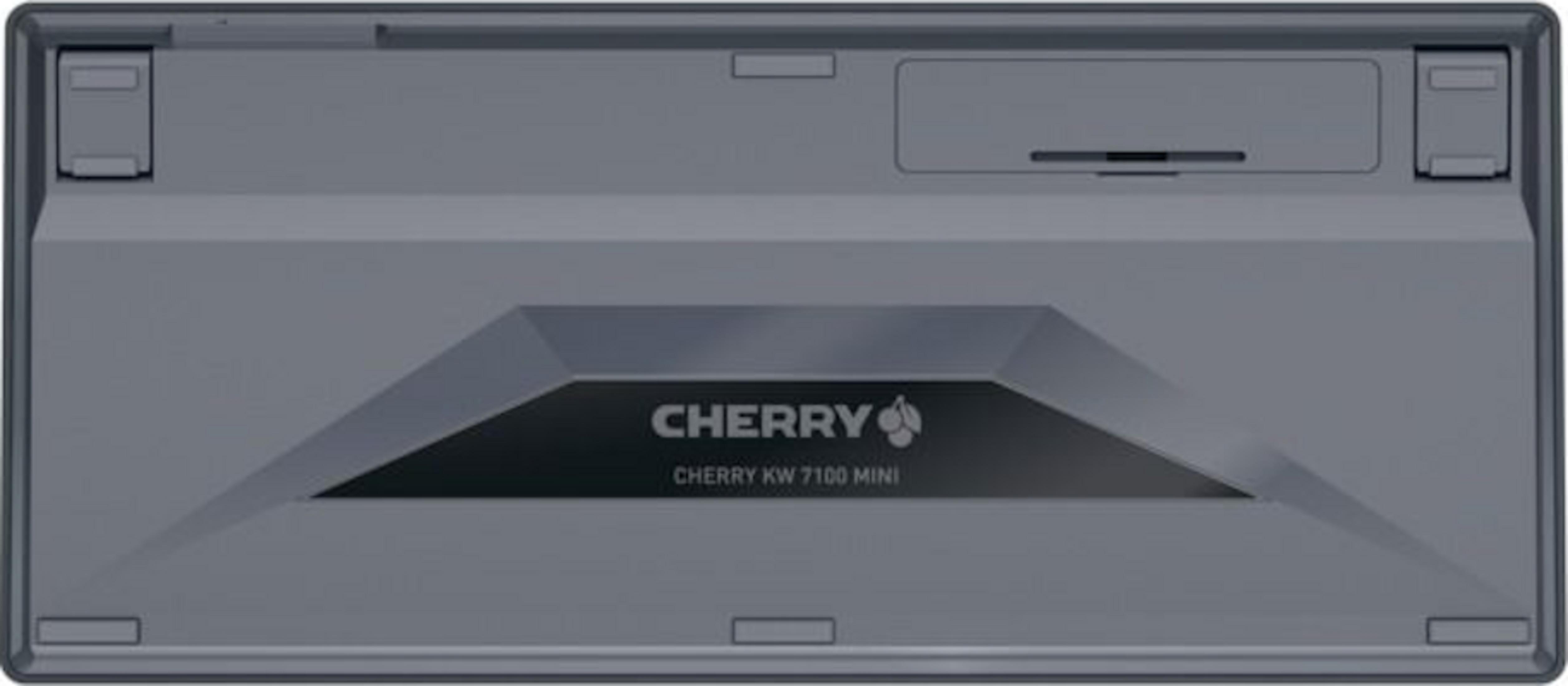 Die Rückseite einer grauen Cherry KW 7100 Mini Tastatur, mit dem Markenlogo und Modellnamen auf einer dunklen rechteckigen Platte.