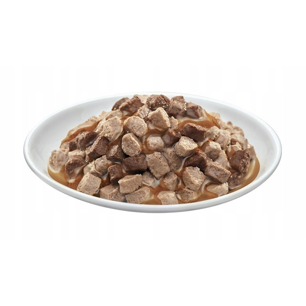 Biała miska z pokrojonym w kostkę mięsem w brązowym sosie.