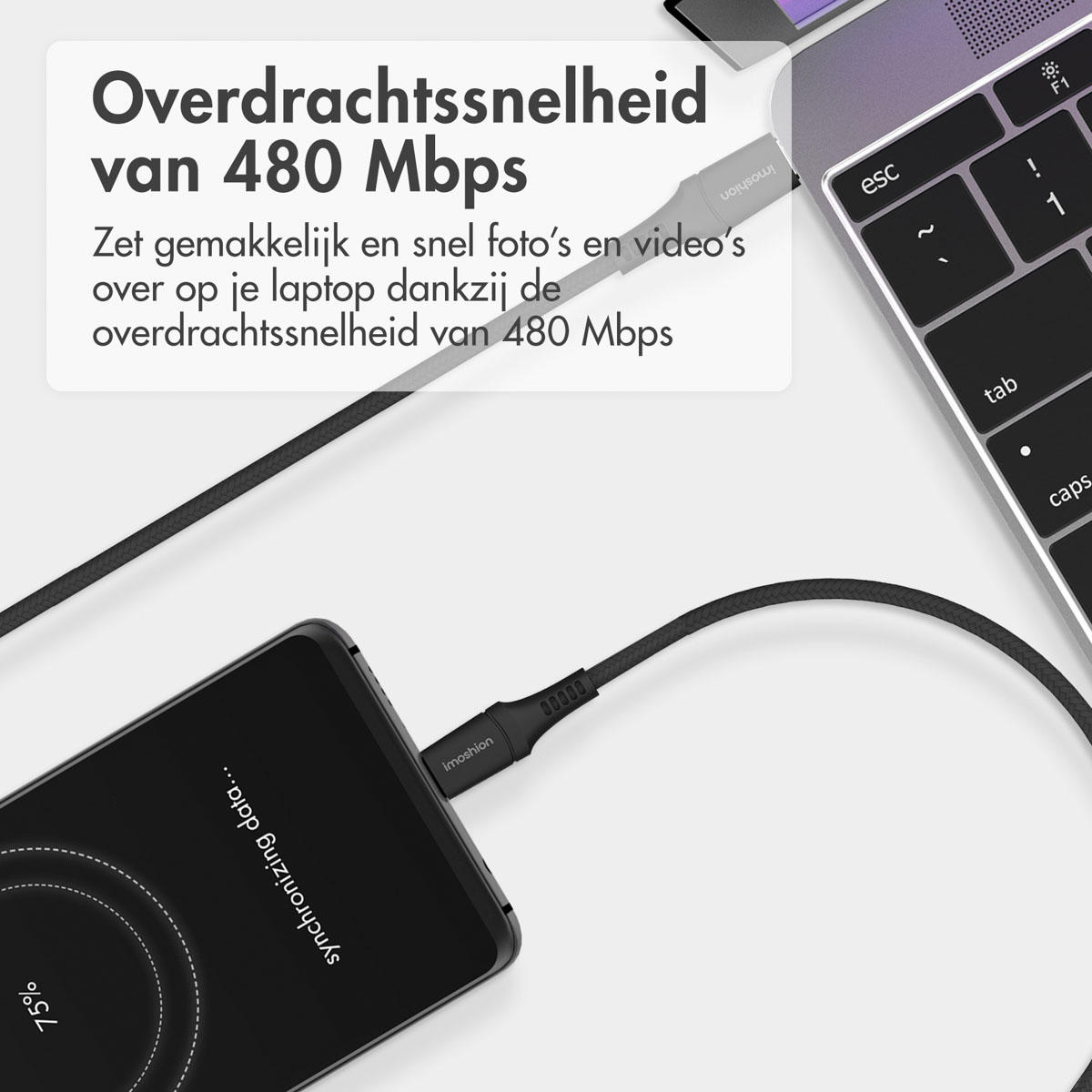 Un smartphone noir connecté à un ordinateur portable argenté avec un câble de données, affichant « Synchronisation des données... 75 % ».