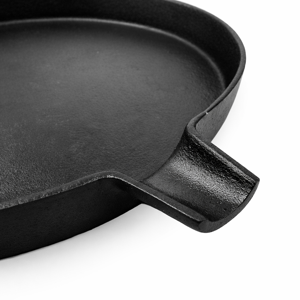Close-up of a black cast iron skillet with a pouring lip. The edge is thick and textured.
