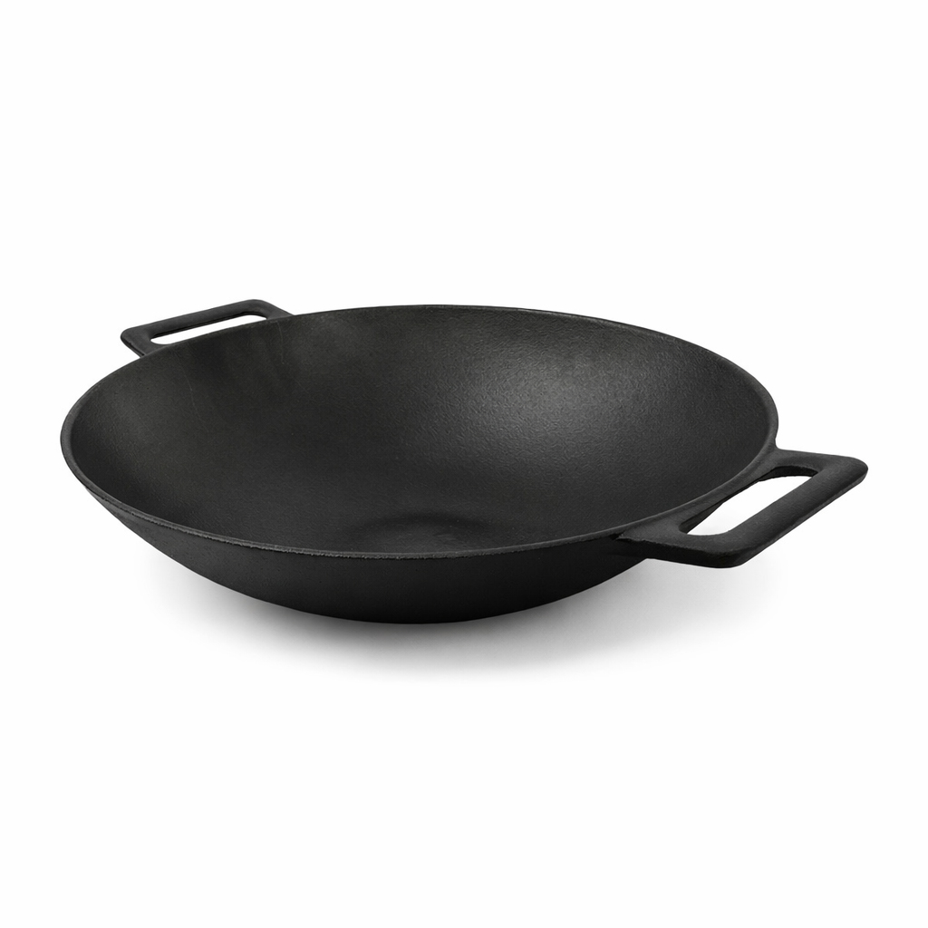 A black cast iron wok with two handles sits on a white background, angled slightly to the right, showing its interior.