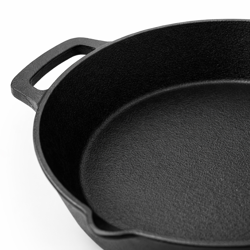 A black cast iron skillet with a handle, set against a white background.