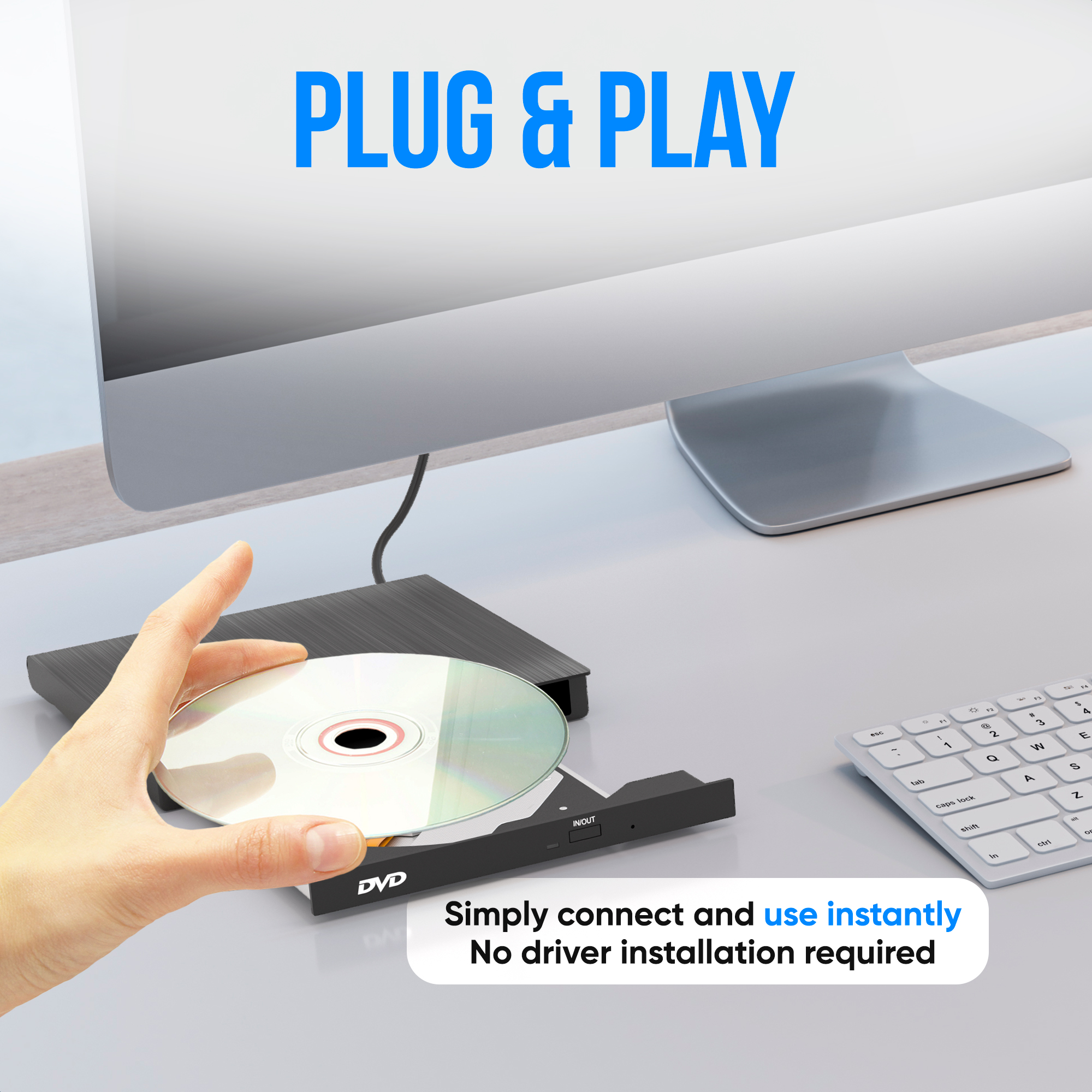 A hand holds a DVD, next to an external DVD player and a keyboard.