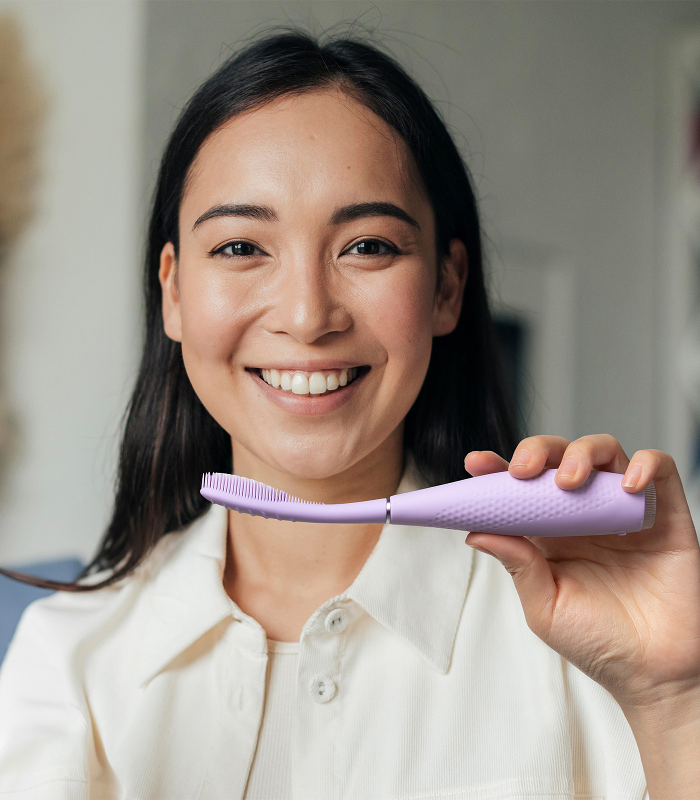 Una donna sorridente tiene uno spazzolino elettrico viola.