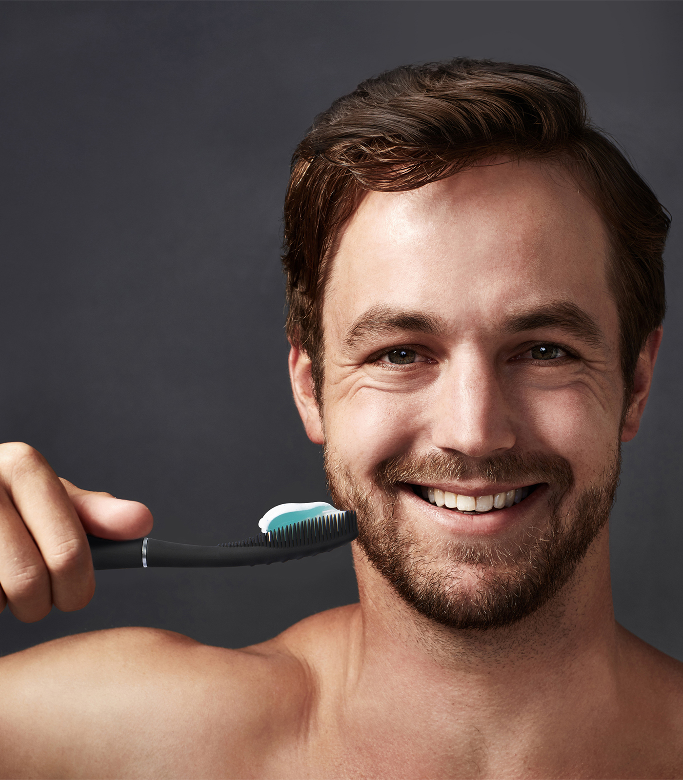 Uomo sorridente con spazzolino e dentifricio.