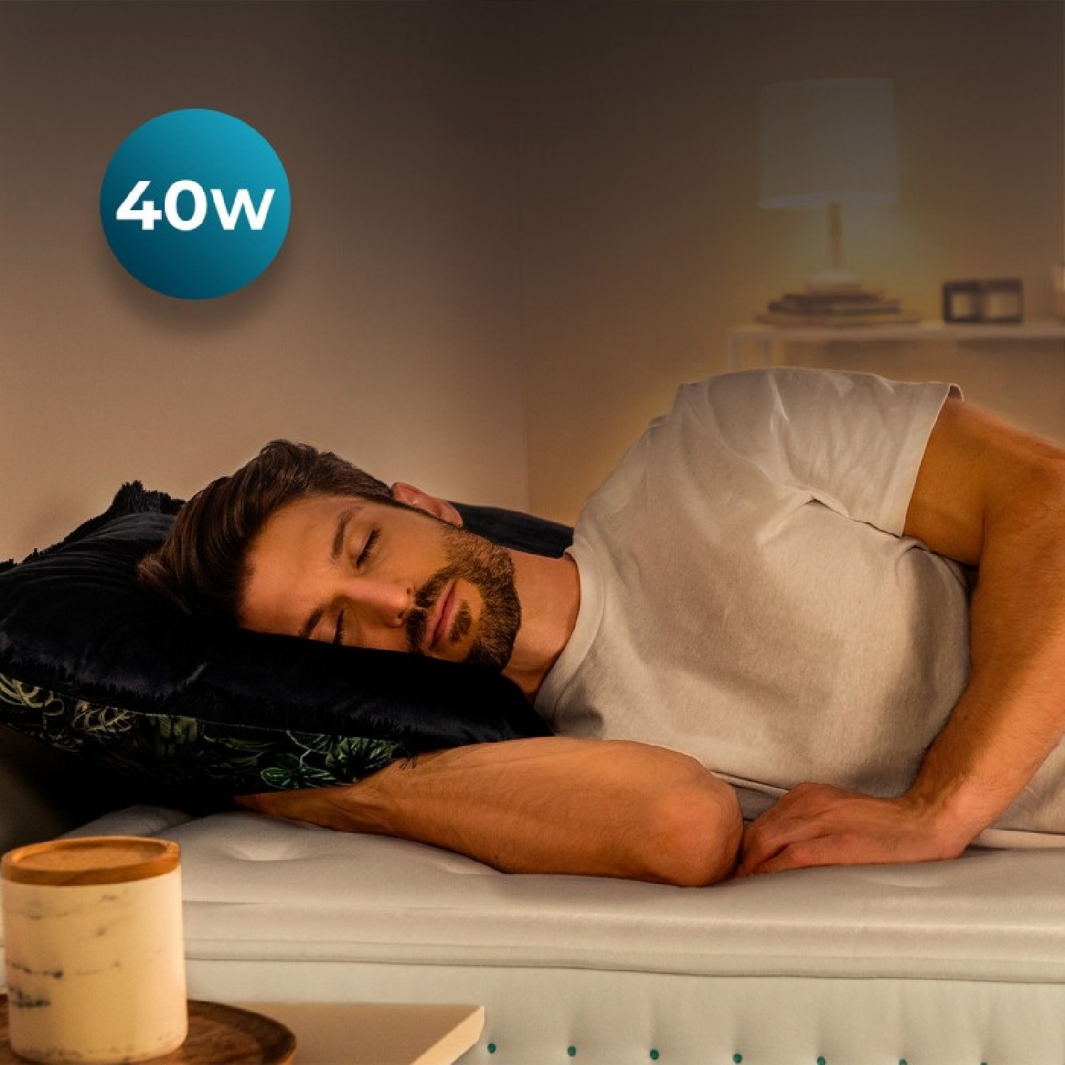 Un uomo dorme su un letto. È visibile un cerchio blu con "40W".