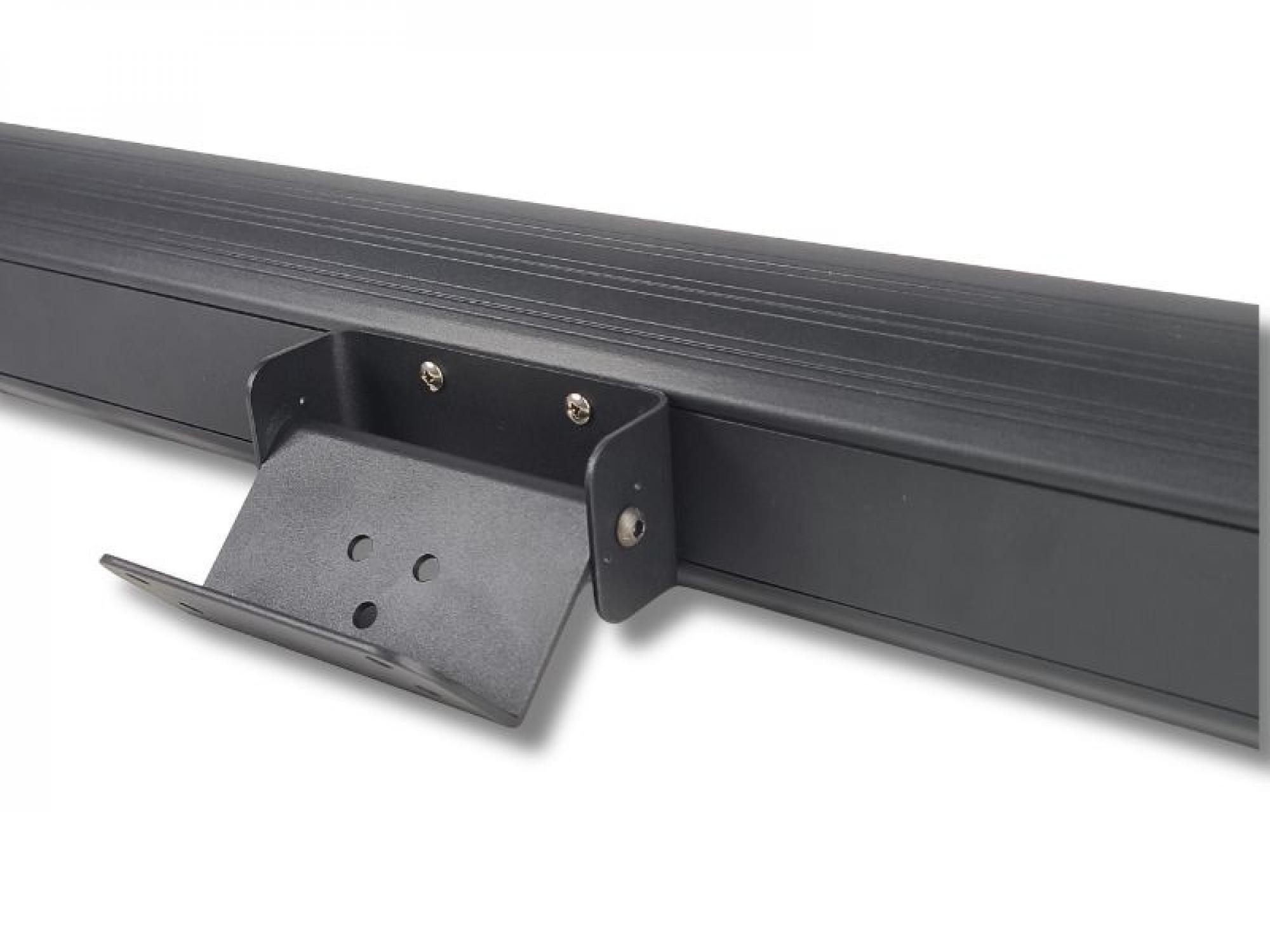 Eine schwarze Metallhalterung ist an einer schwarzen, gerippten Oberfläche, wahrscheinlich einem Projektorleinwandgehäuse, vor weißem Hintergrund befestigt.