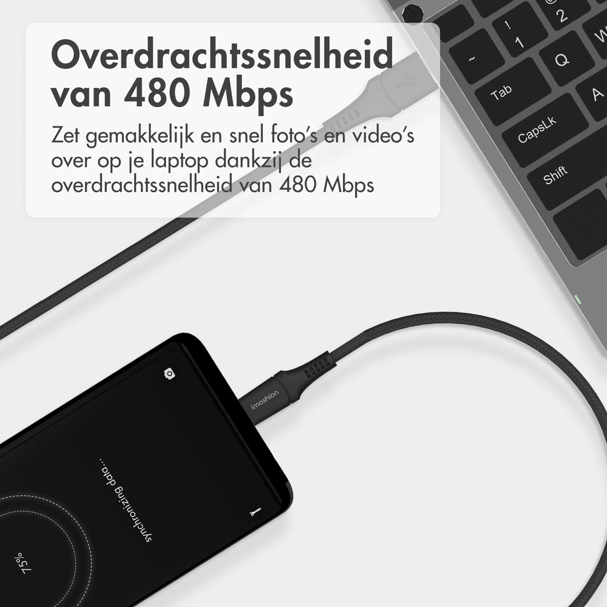 Un smartphone noir affichant "synchronizing data", connecté à un ordinateur portable via un câble USB tressé noir.