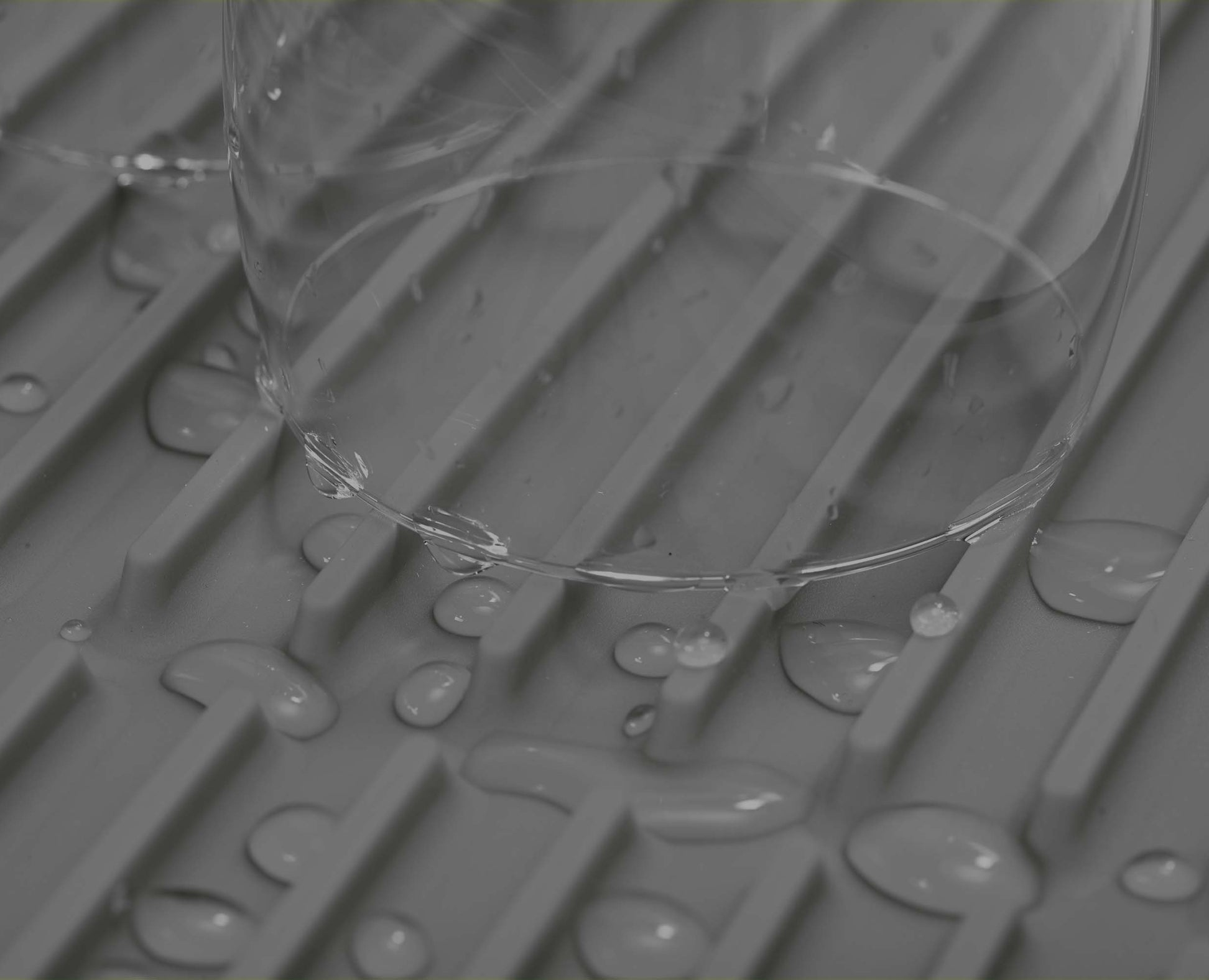 Gocce d'acqua su una griglia grigia con bordo di vetro.