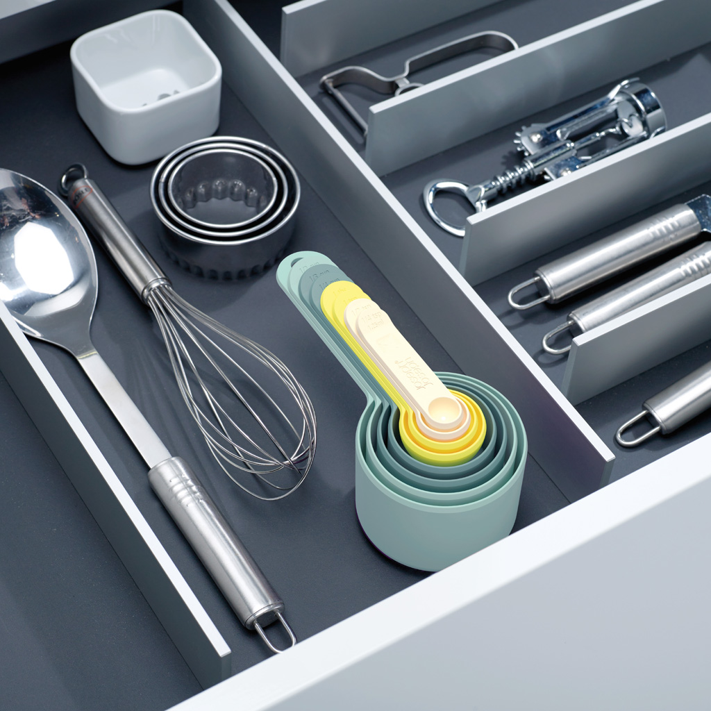 Utensili da cucina in un cassetto: cucchiaio, frusta, misurini, formine, cavatappi.