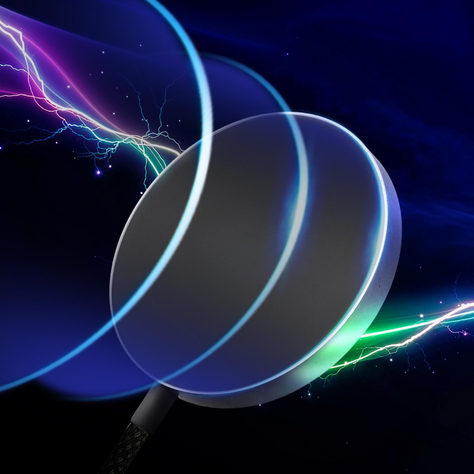 Okrągły obiekt z niebieskimi i zielonymi łukami światła na ciemnym tle.