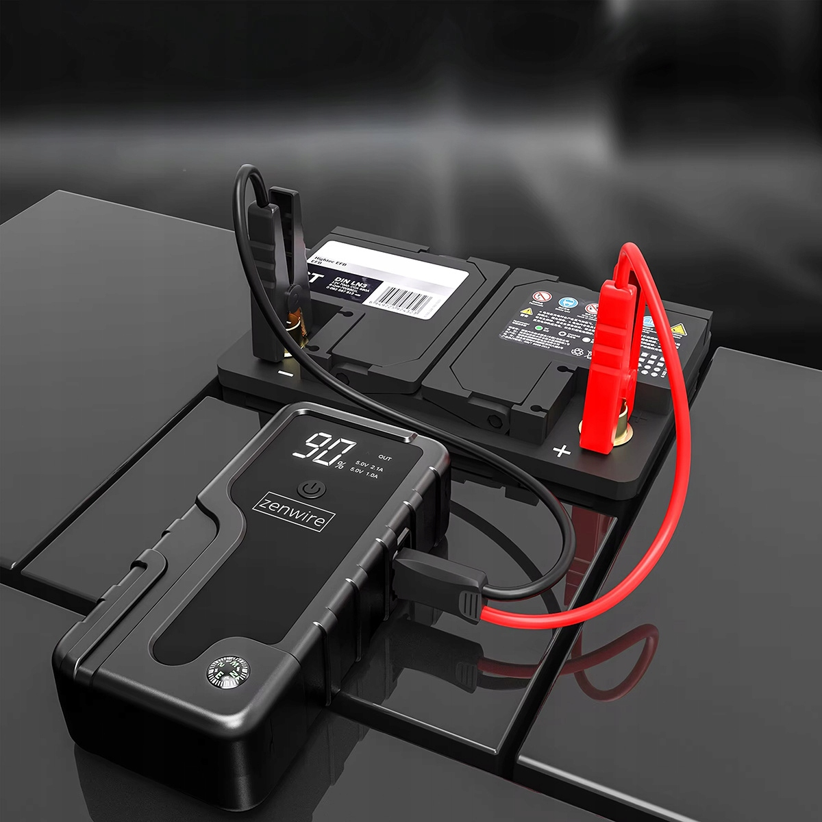 Un avviatore di emergenza nero carica una batteria per auto con morsetti rossi e neri.