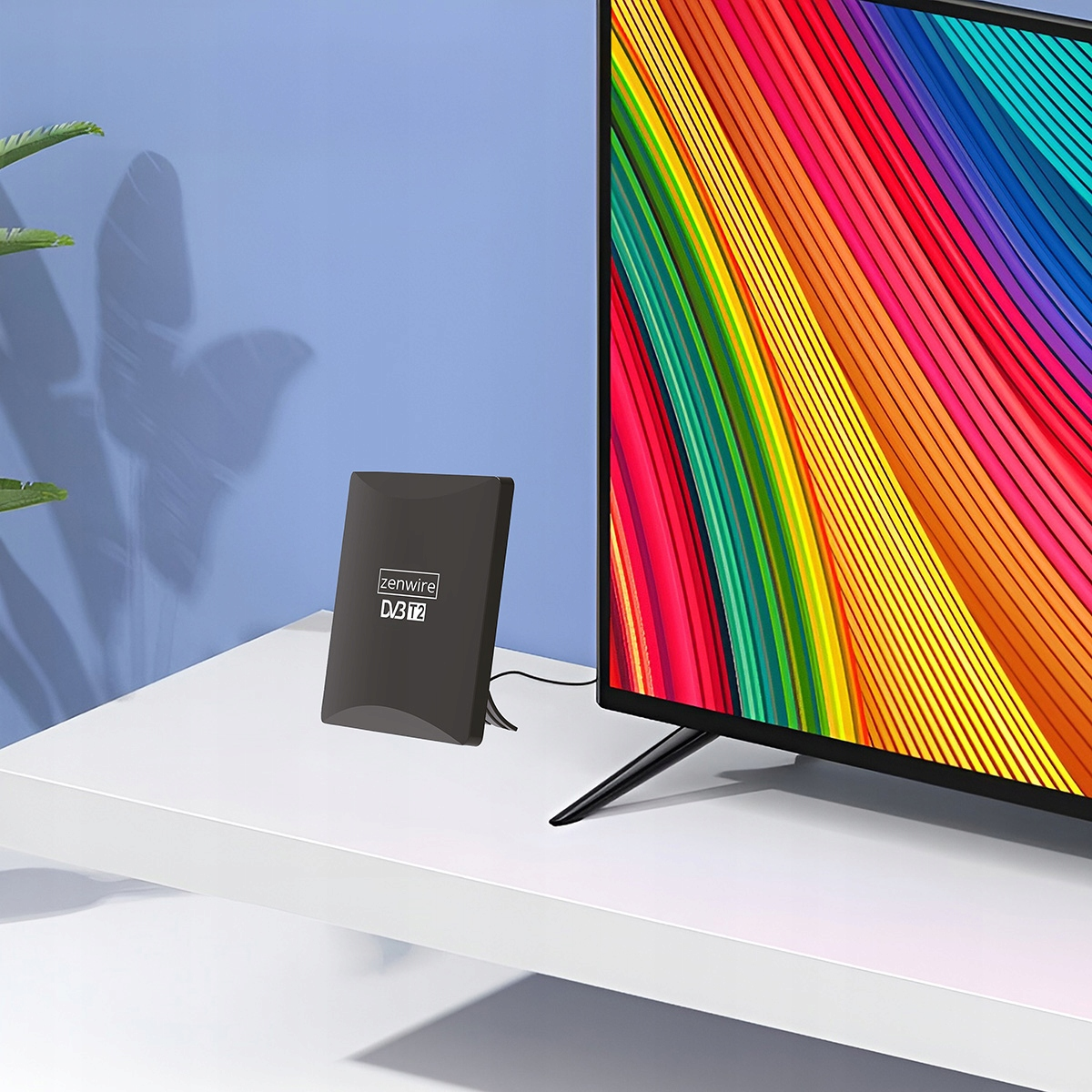 Czarny odbiornik DVB T2 obok telewizora z kolorowym ekranem.
