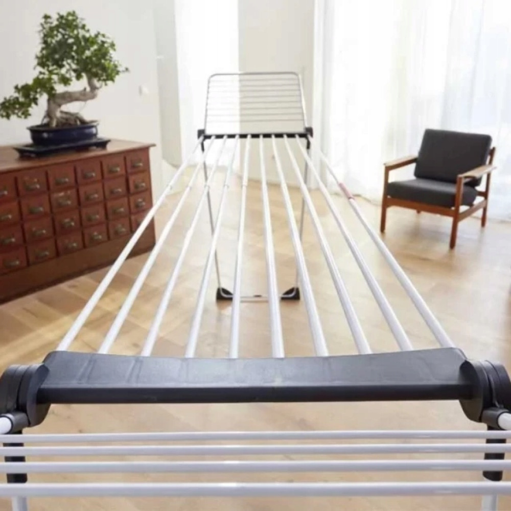 Stojak na pranie stoi w pokoju obok szafki i fotela.