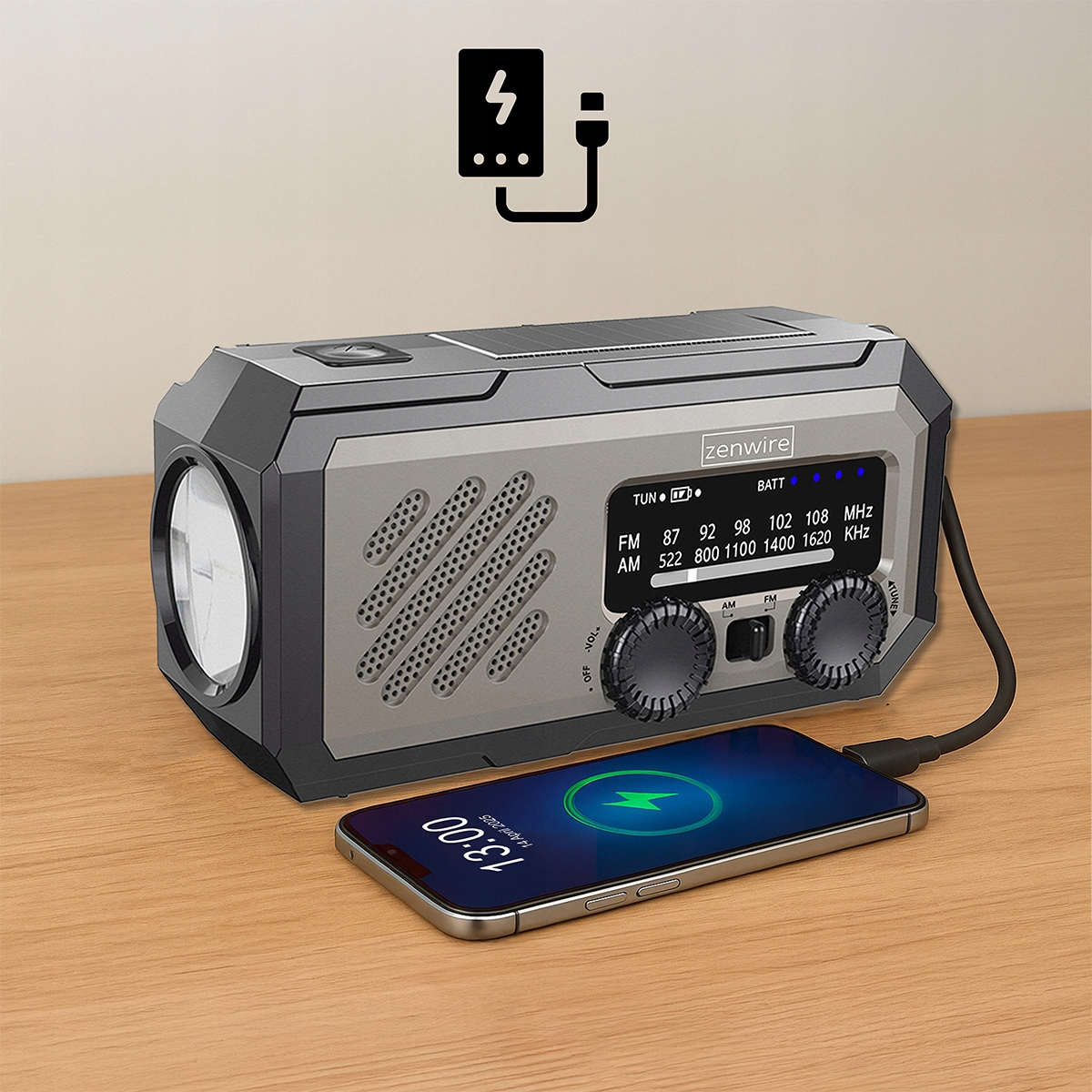 Radio z latarką ładuje telefon komórkowy na drewnianym stole.