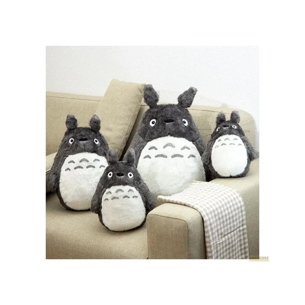 Quattro peluche Totoro di varie dimensioni seduti su un divano.