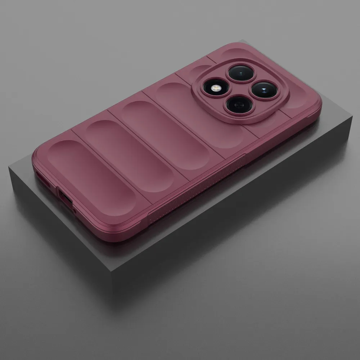 Une coque de téléphone bordeaux à quatre objectifs photo repose sur un piédestal gris.