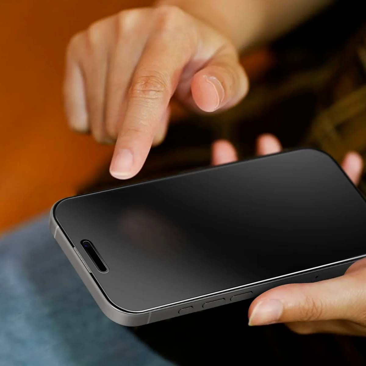 Hands hold and operate a smartphone with a black screen.