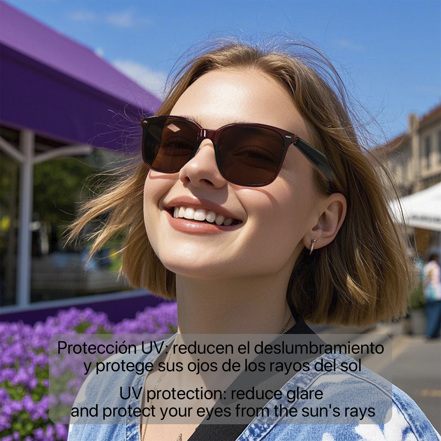 Donna sorridente con occhiali da sole, fiori viola e edifici sullo sfondo.